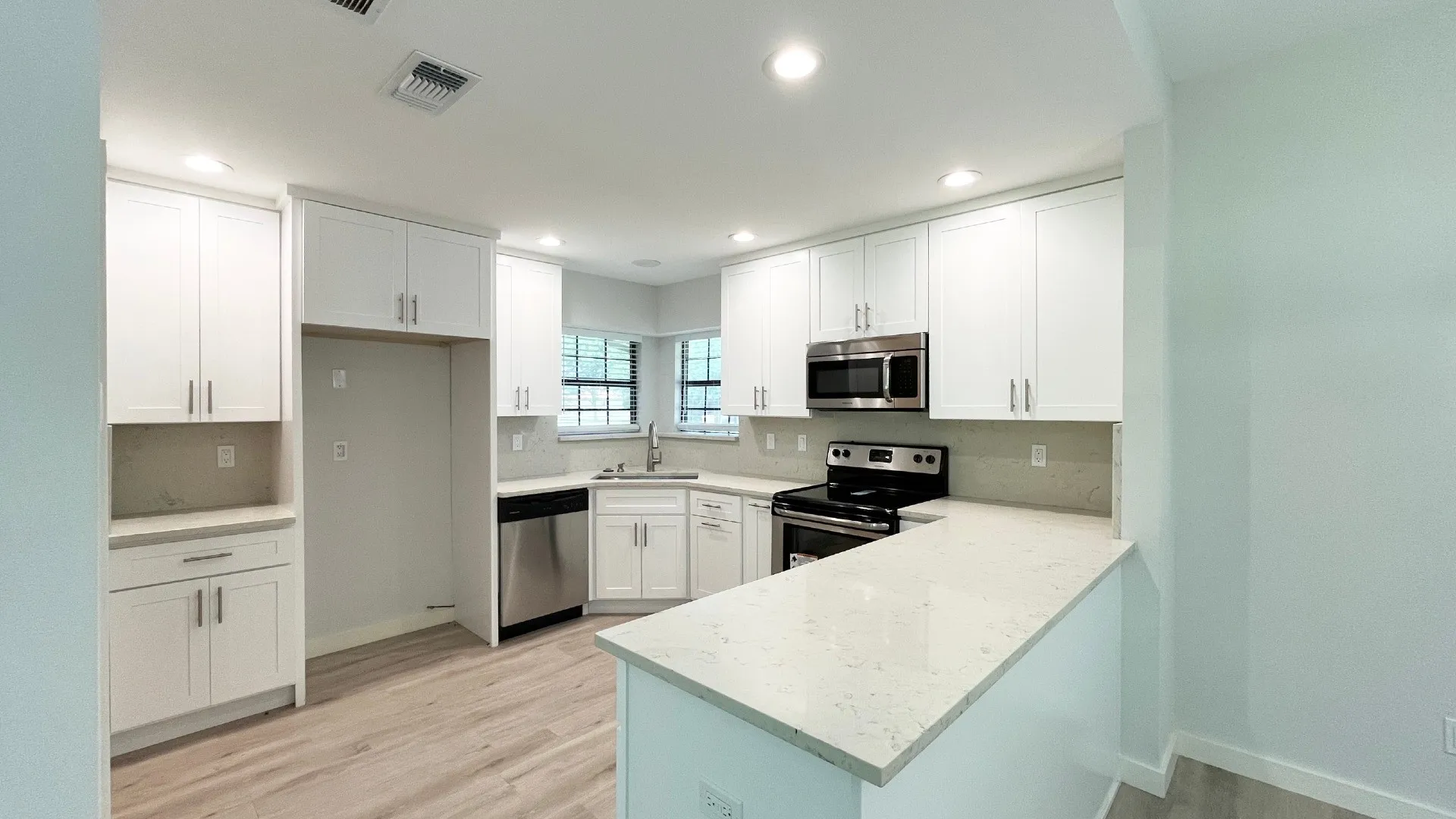 Contemporary kitchen featuring white cabinetry, light-toned countertops, stainless steel appliances, and recessed lighting