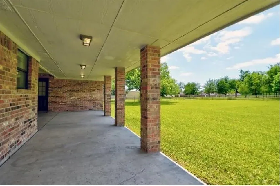 Spacious covered patio with concrete flooring, brick columns, and recessed lighting