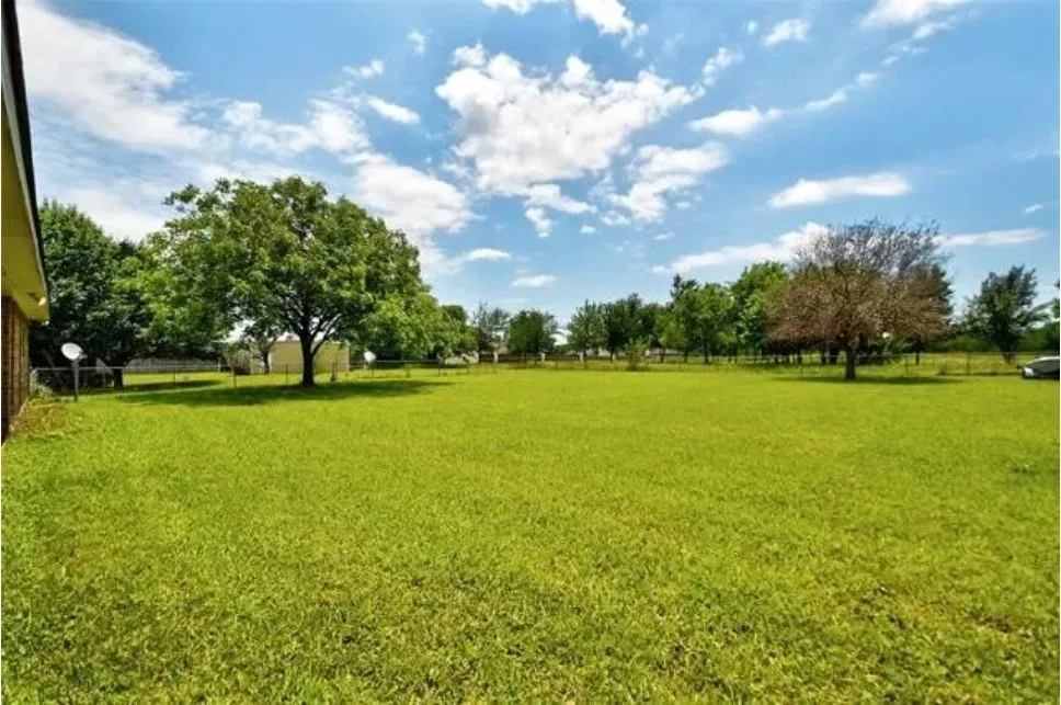 Expansive lawn with mature trees and perimeter fencing