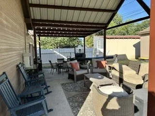 Paved patio area featuring a metal-framed overhead structure with a corrugated roof