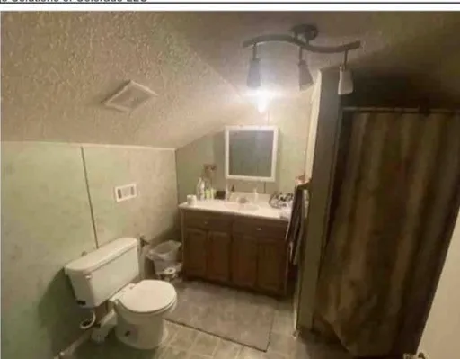 Bathroom featuring a toilet, vanity with integrated sink, and track lighting fixture