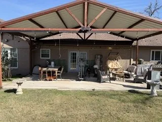 Expansive concrete patio with a large covered pergola featuring exposed wood beams and integrated string lighting