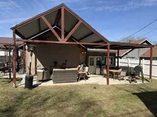 Expansive outdoor living area featuring a covered patio, gabled patio roof structure, and double French doors accessing the interior
