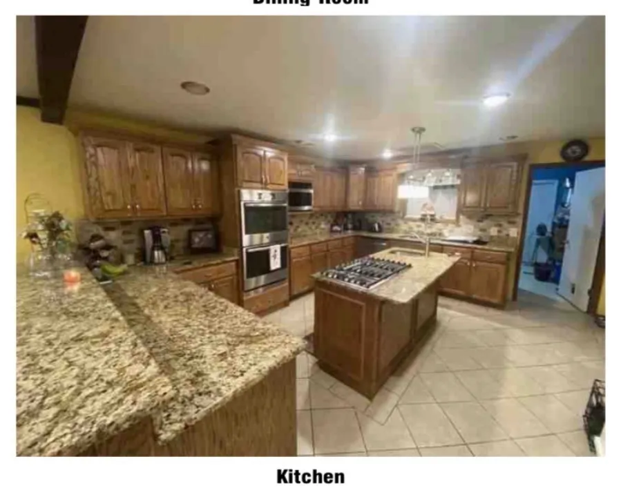 Kitchen featuring wood cabinetry, granite countertops, stainless steel double ovens, a central island with a gas cooktop, and tile flooring