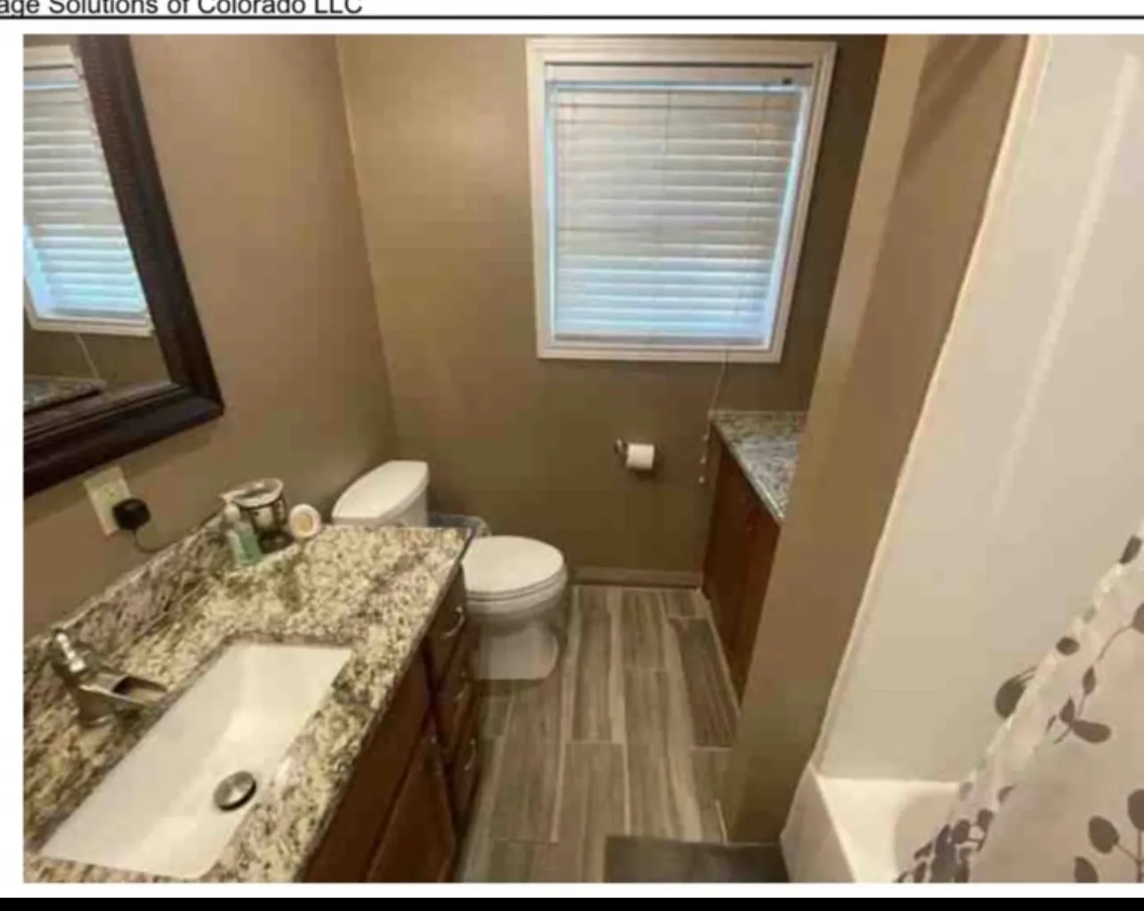 Bathroom featuring a vanity with a granite-style countertop, integrated rectangular sink, wood-finish cabinetry, and wood-look tile flooring
