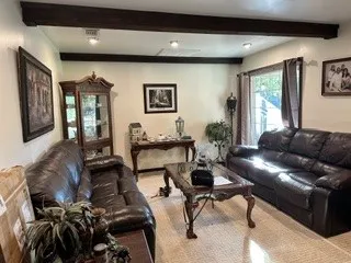 Exposed ceiling beams, recessed lighting, wall-mounted artwork, and window with drapes