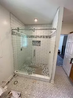 Glass-enclosed shower with subway tile walls, a mosaic tile accent band, and a built-in shower niche