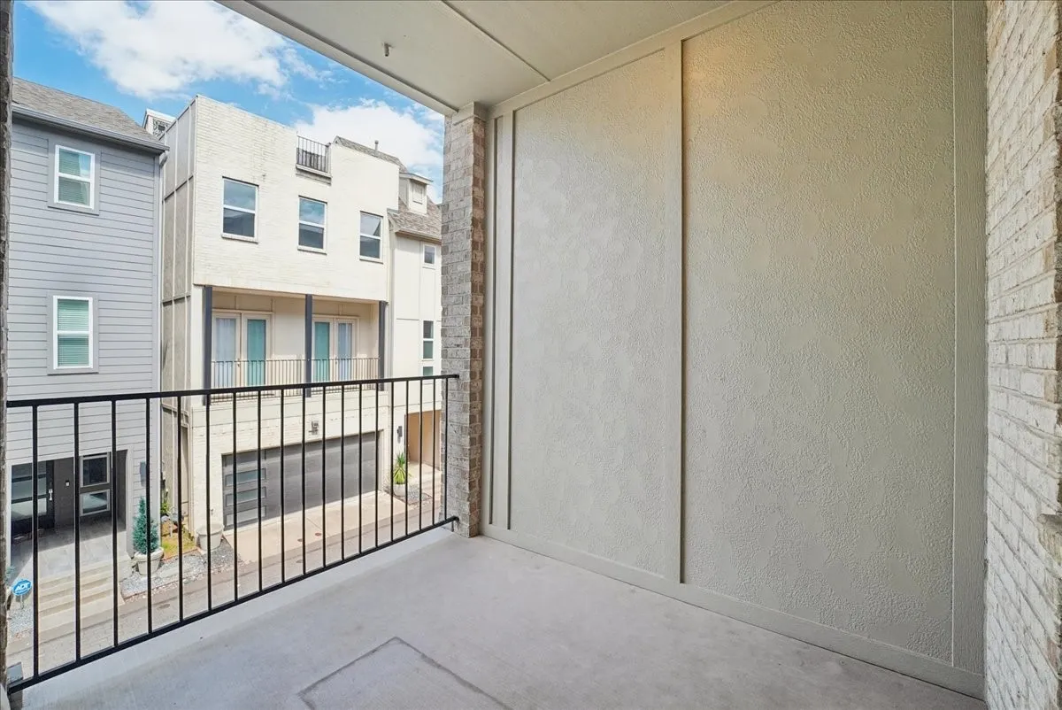 Balcony featuring a concrete floor, black metal railing, and brick exterior wall