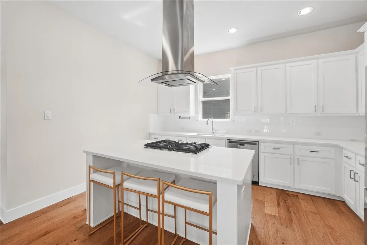 Kitchen featuring white cabinetry, a large kitchen island, stainless steel range hood, built-in cooktop, and wood-finish flooring