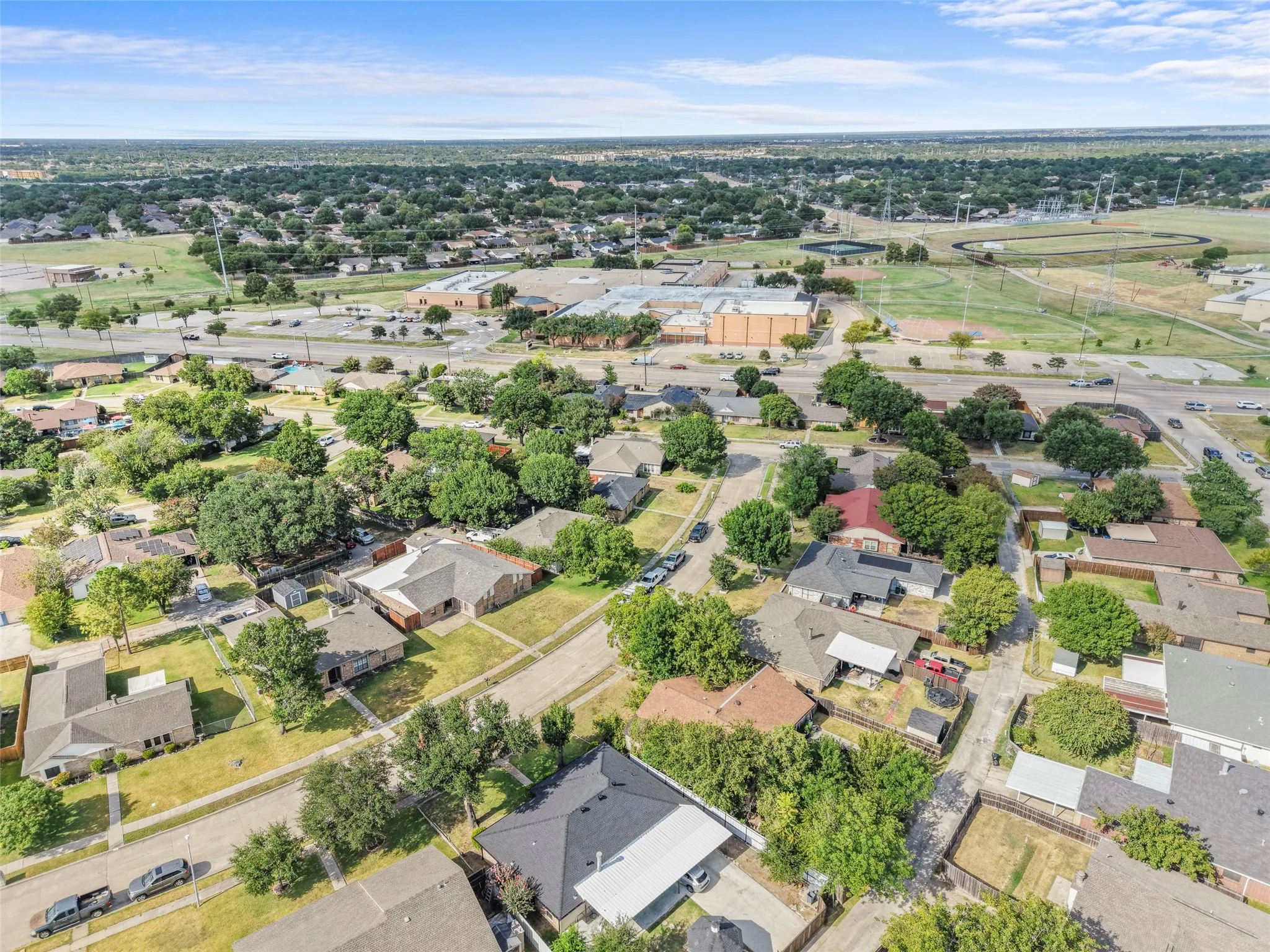Aerial perspective showcasing a residential neighborhood with established trees, multiple detached homes, and paved streets