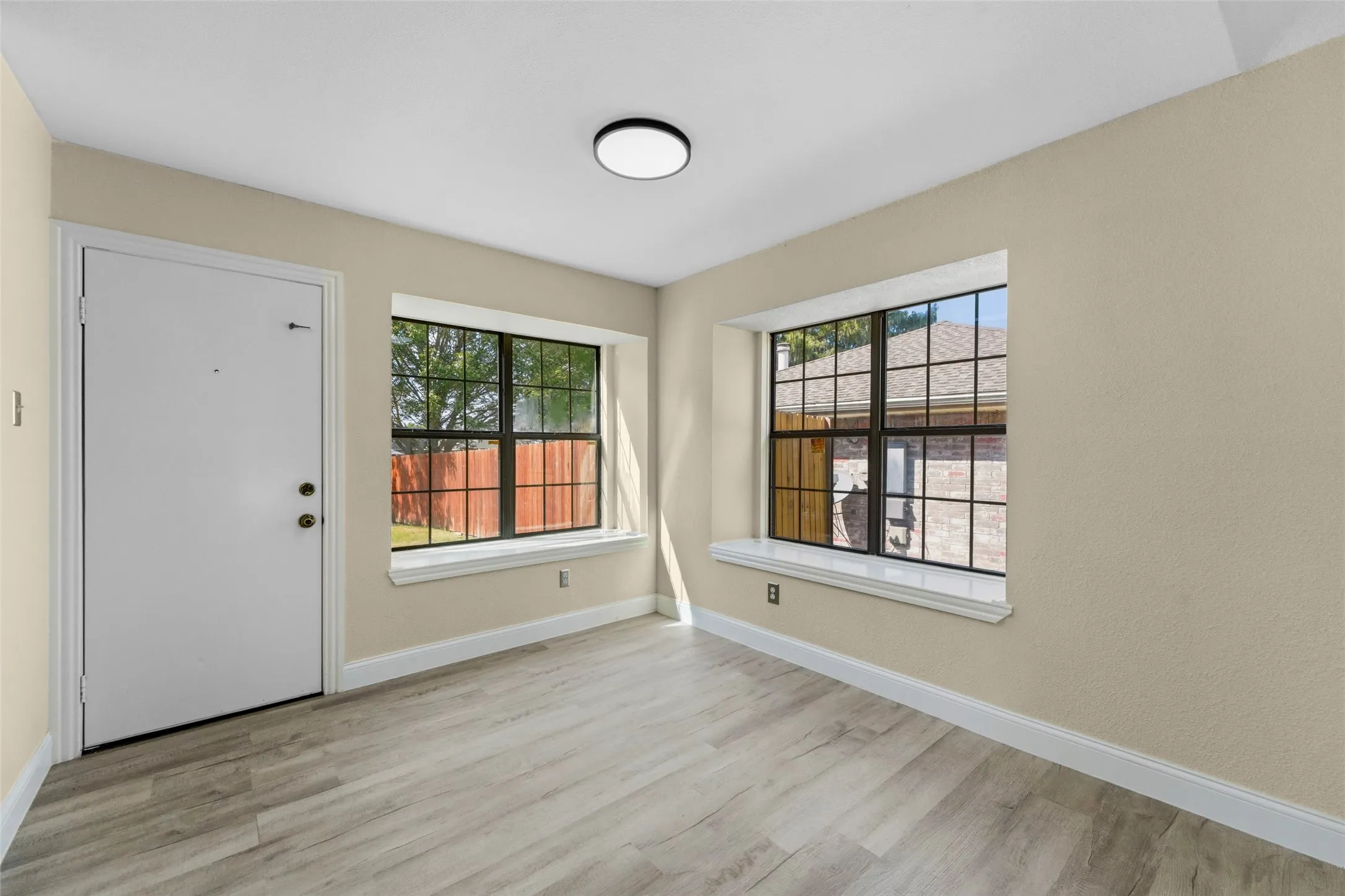 Entryway with wood-finish flooring, two large windows, and a flush-mount ceiling light
