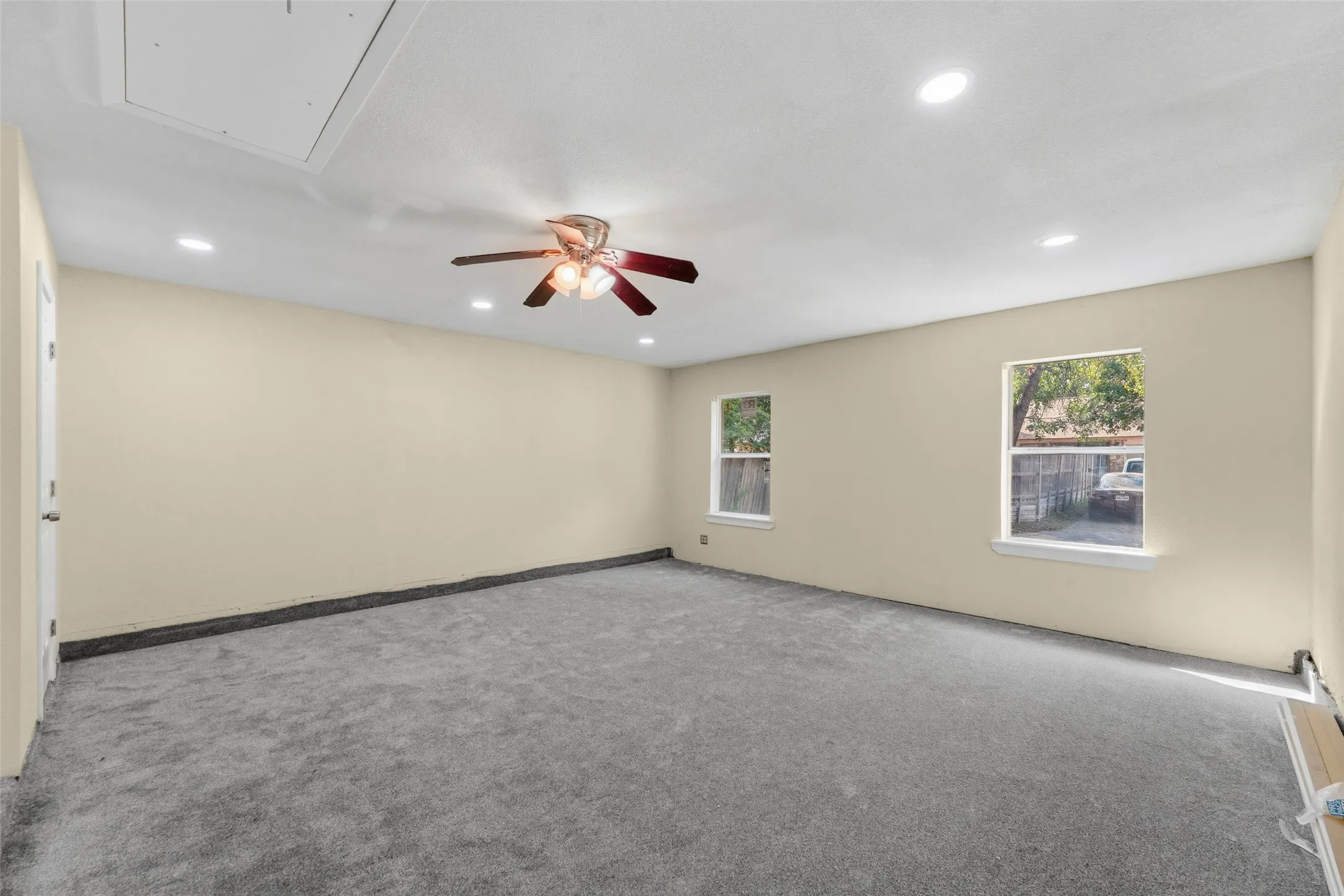 Recessed lighting, ceiling fan, two windows, and light-toned walls