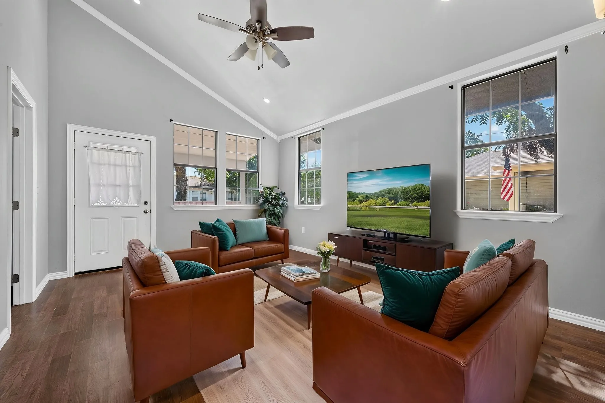 Vaulted ceiling with a ceiling fan, recessed lighting, wood-look finish flooring, and multiple windows with white trim