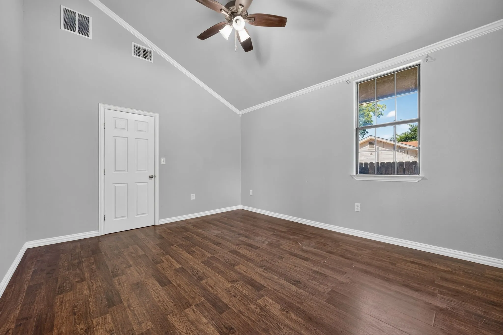 Vaulted ceiling, wood-look finish flooring, ceiling fan, crown molding, and window with exterior view