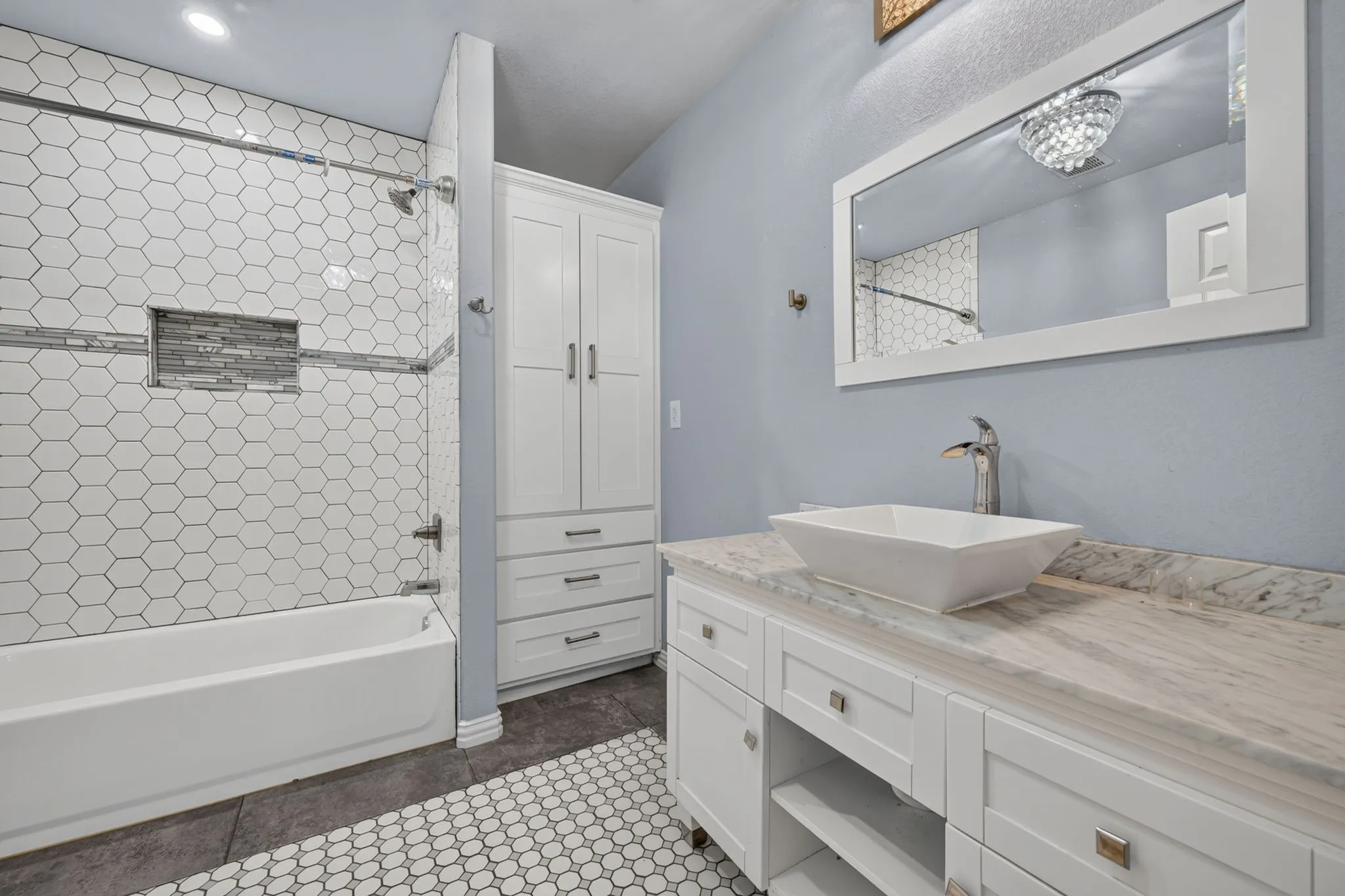 White hexagonal tile shower surround with a tiled niche and a showerhead