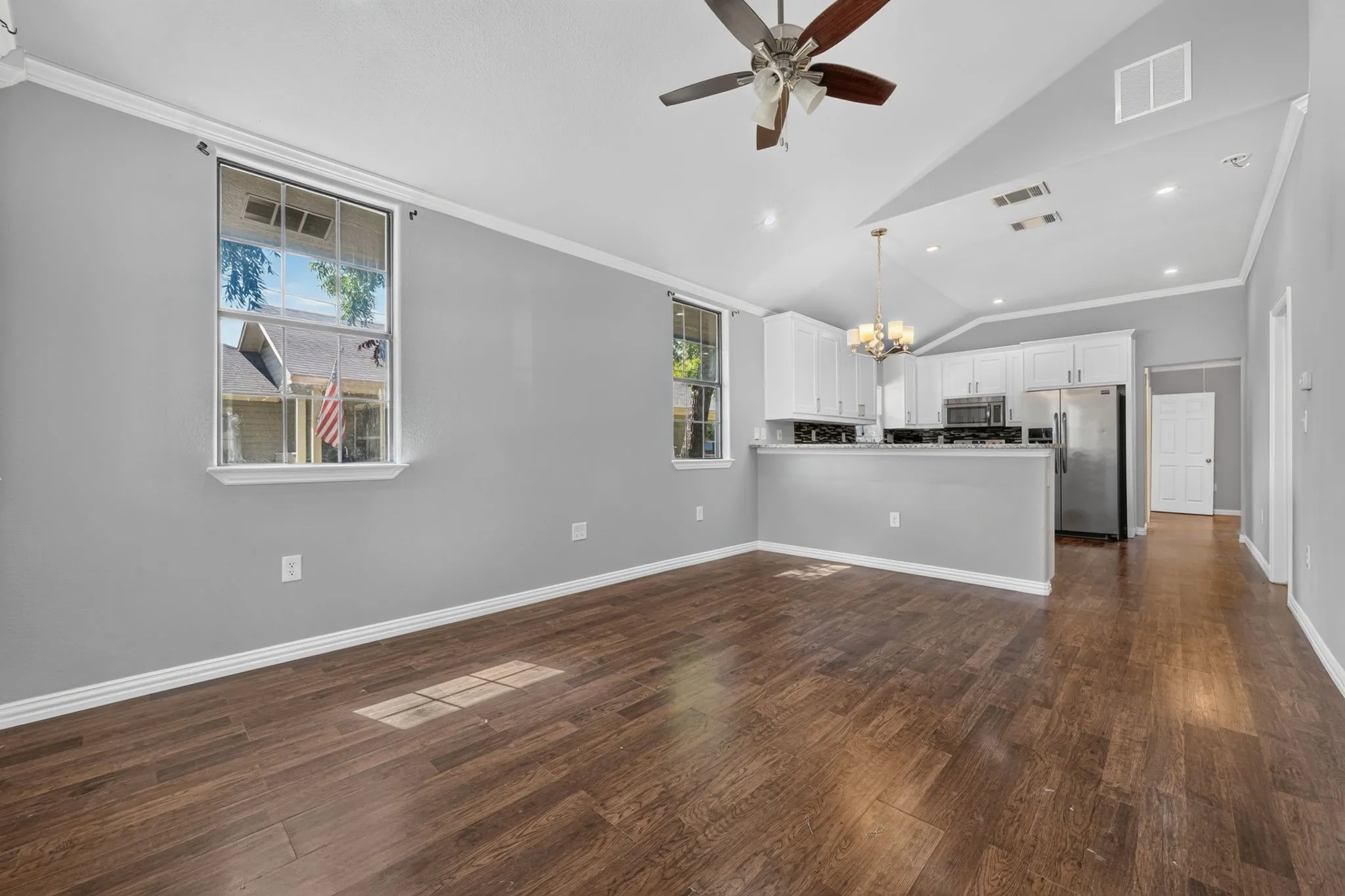 Open-concept living area featuring wood-look
finish flooring, vaulted ceilings, and a ceiling fan