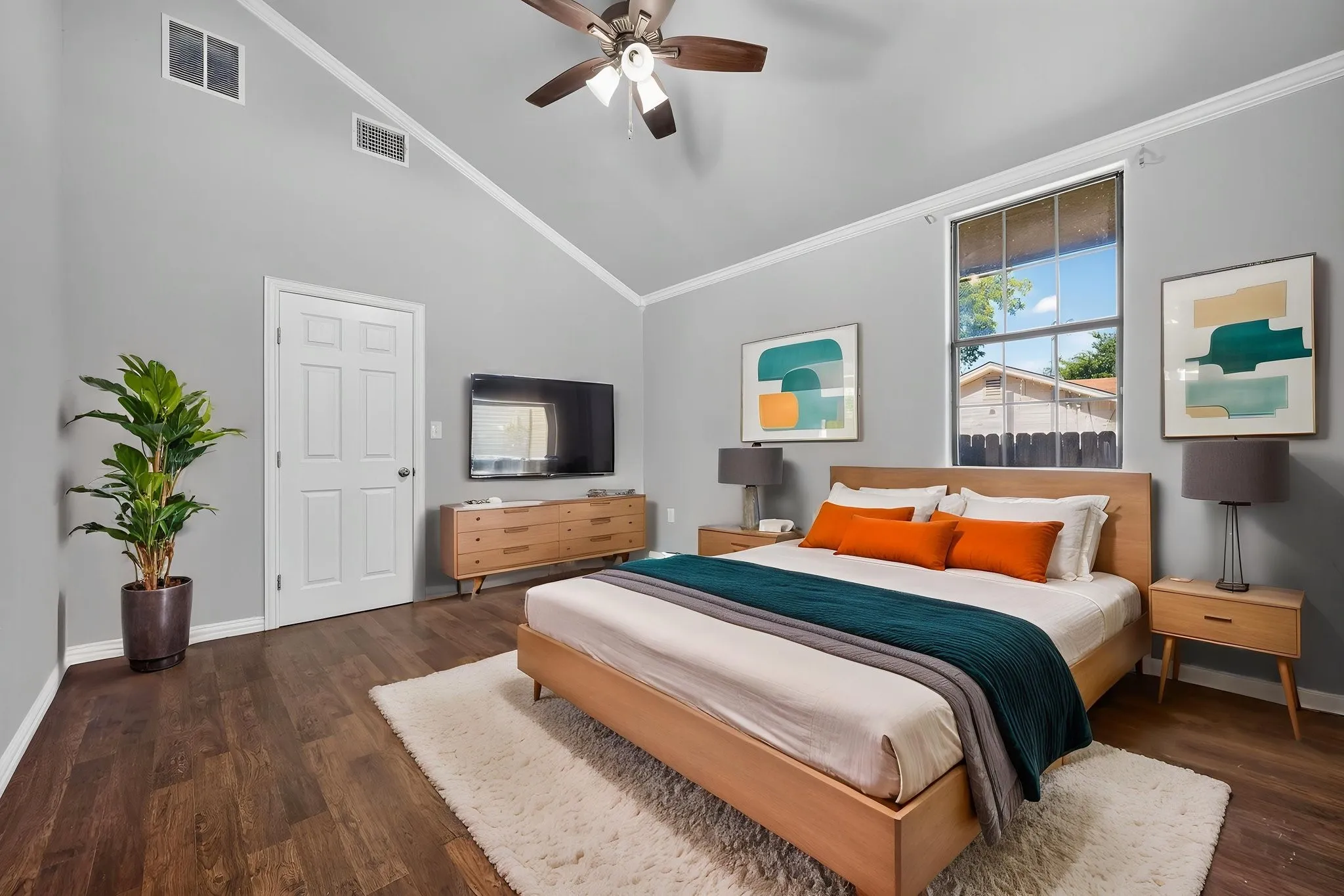Vaulted ceiling with crown molding, wood look-finish flooring, ceiling fan with light fixture, and a window with blinds