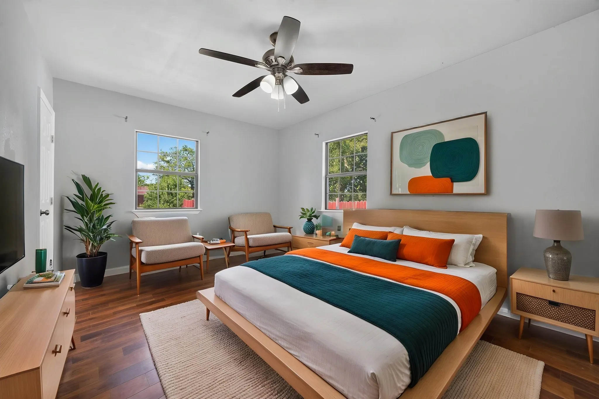 Wood-look finish flooring, light grey wall paint, two windows, and a ceiling fan with integrated lighting