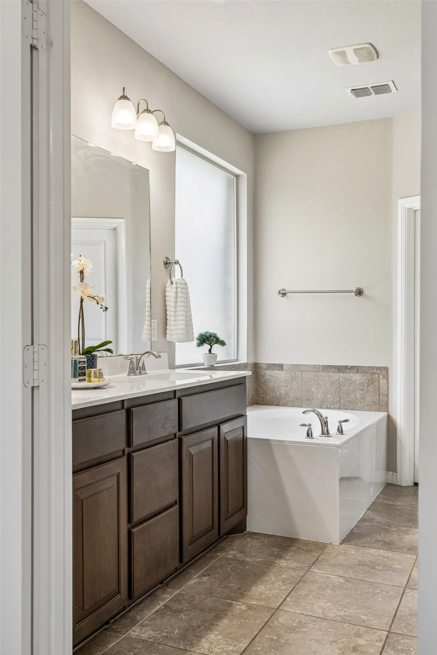 Spa-inspired primary bathroom featuring a dark wood vanity with dual sinks, white quartz countertop, and polished nickel fixtures