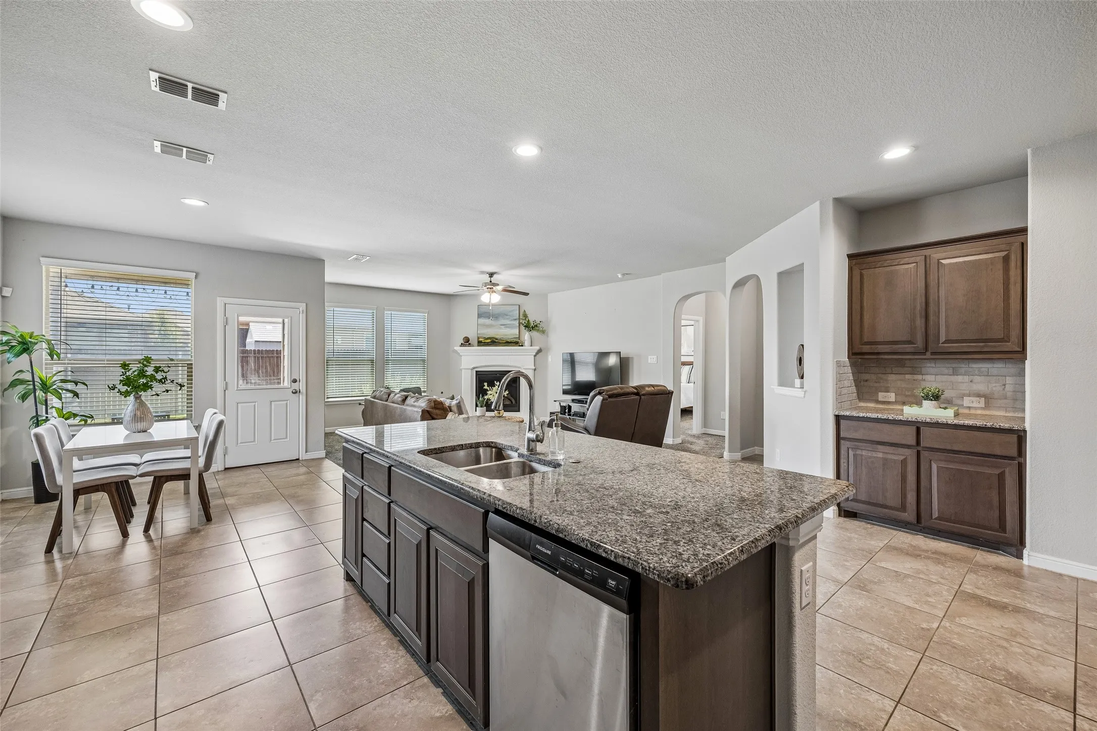 Expansive open-concept kitchen featuring a large island with an undermount double sink, granite countertops, and tile flooring