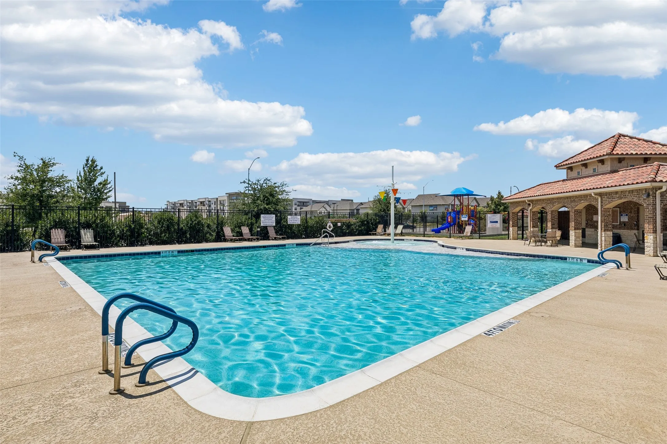 Community swimming pool with an adjacent covered pavilion, a splash pad, and a playground structure