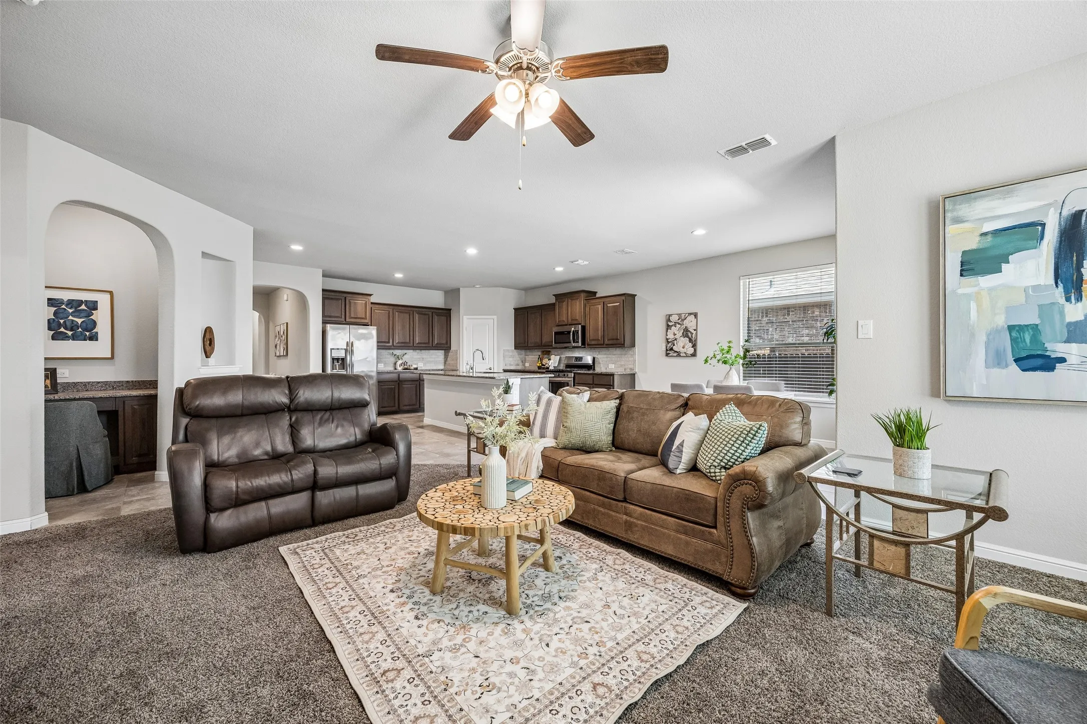 Open-concept living area featuring a ceiling fan, recessed lighting, and arched doorways
