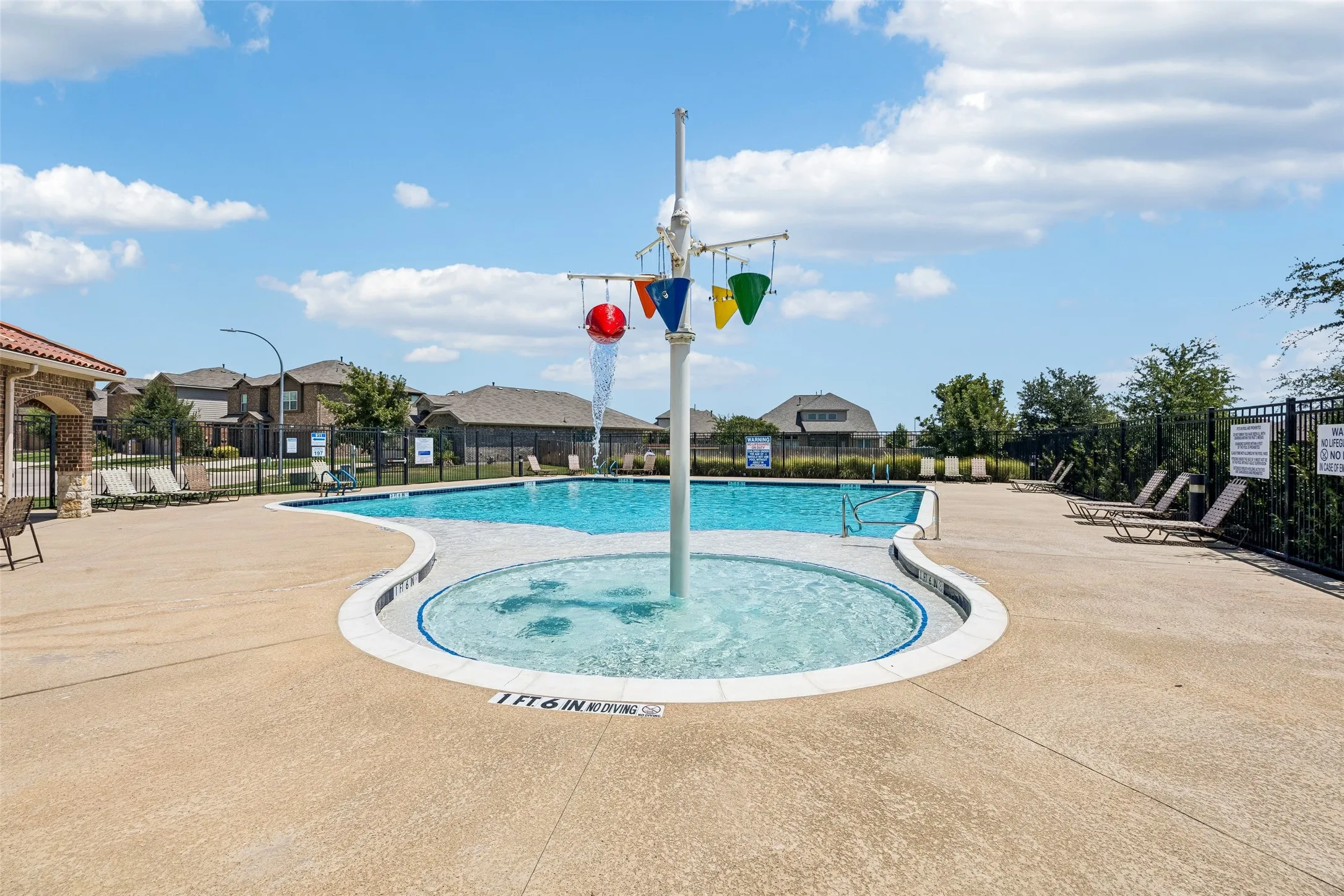 Community aquatic center featuring a zero-entry splash pad with interactive water play elements, Olympic-length lap pool with multiple lanes, and sun deck with lounge seating