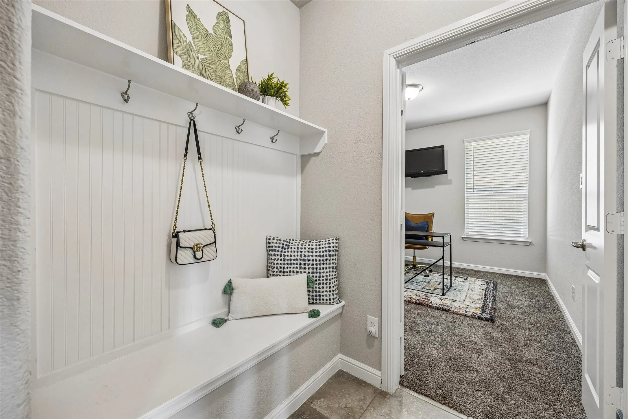 Built-in storage bench with beadboard backing and upper shelf, located just off the garage