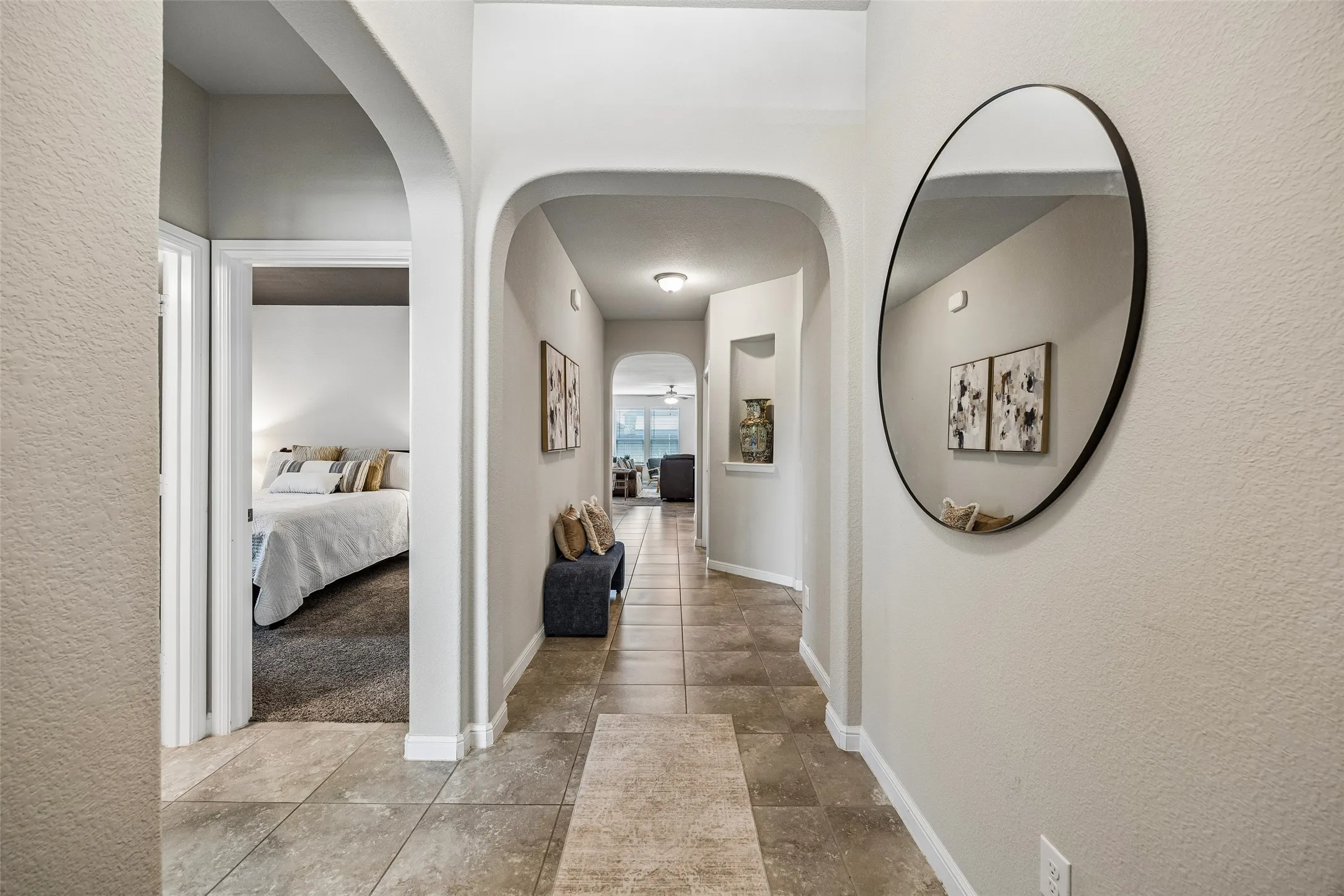 Large entry featuring arched doorways, neutral wall paint, tile flooring, and recessed lighting. Room on left is guest bedroom