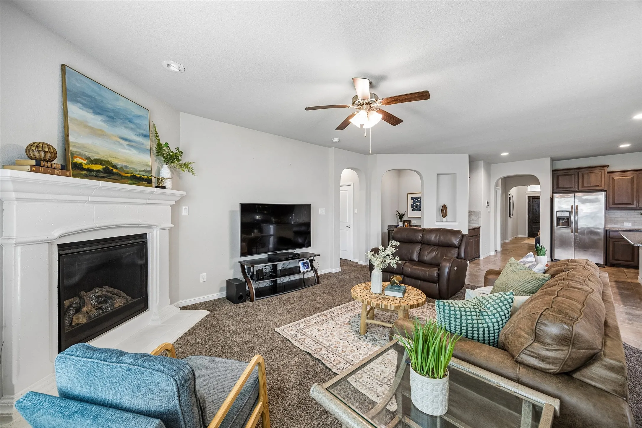 Living room featuring a fireplace with a white mantel, recessed lighting, a ceiling fan, and carpet flooring