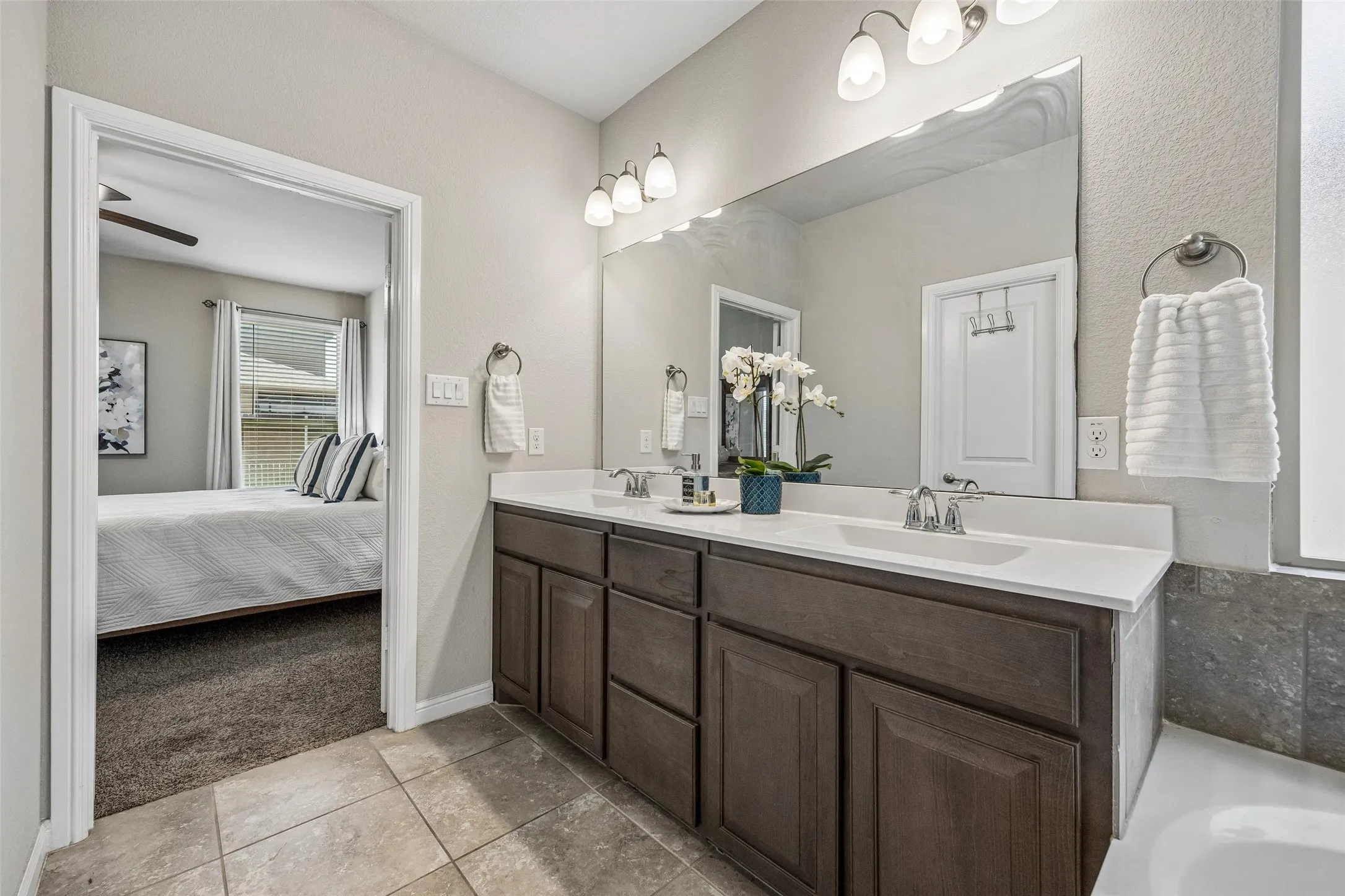 Double vanity with wood-finish cabinetry, white countertop, and integrated sinks