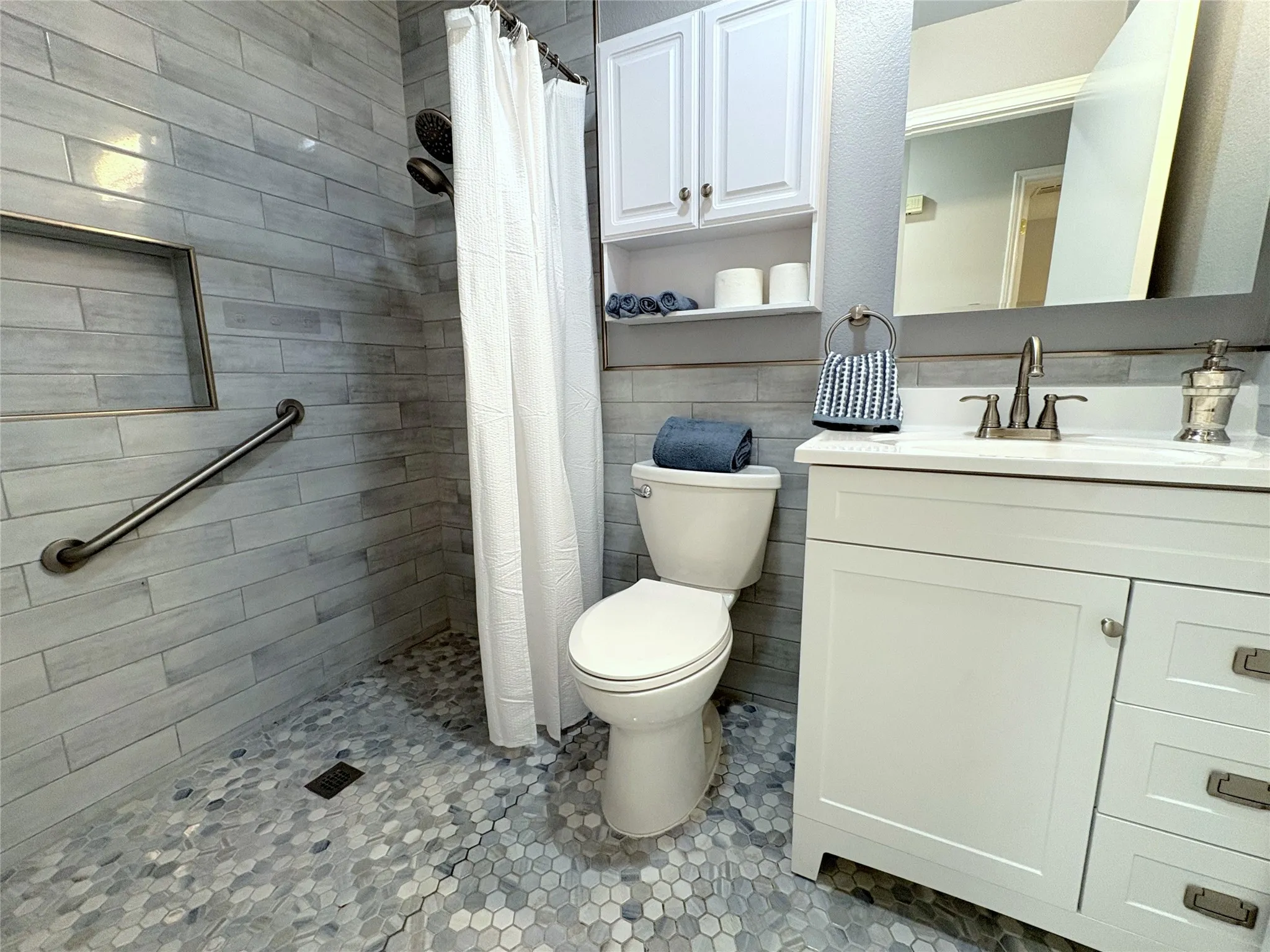 The hall bath is wheelchair accessible and features an upated vanity and beautiful tiled walk-in shower.