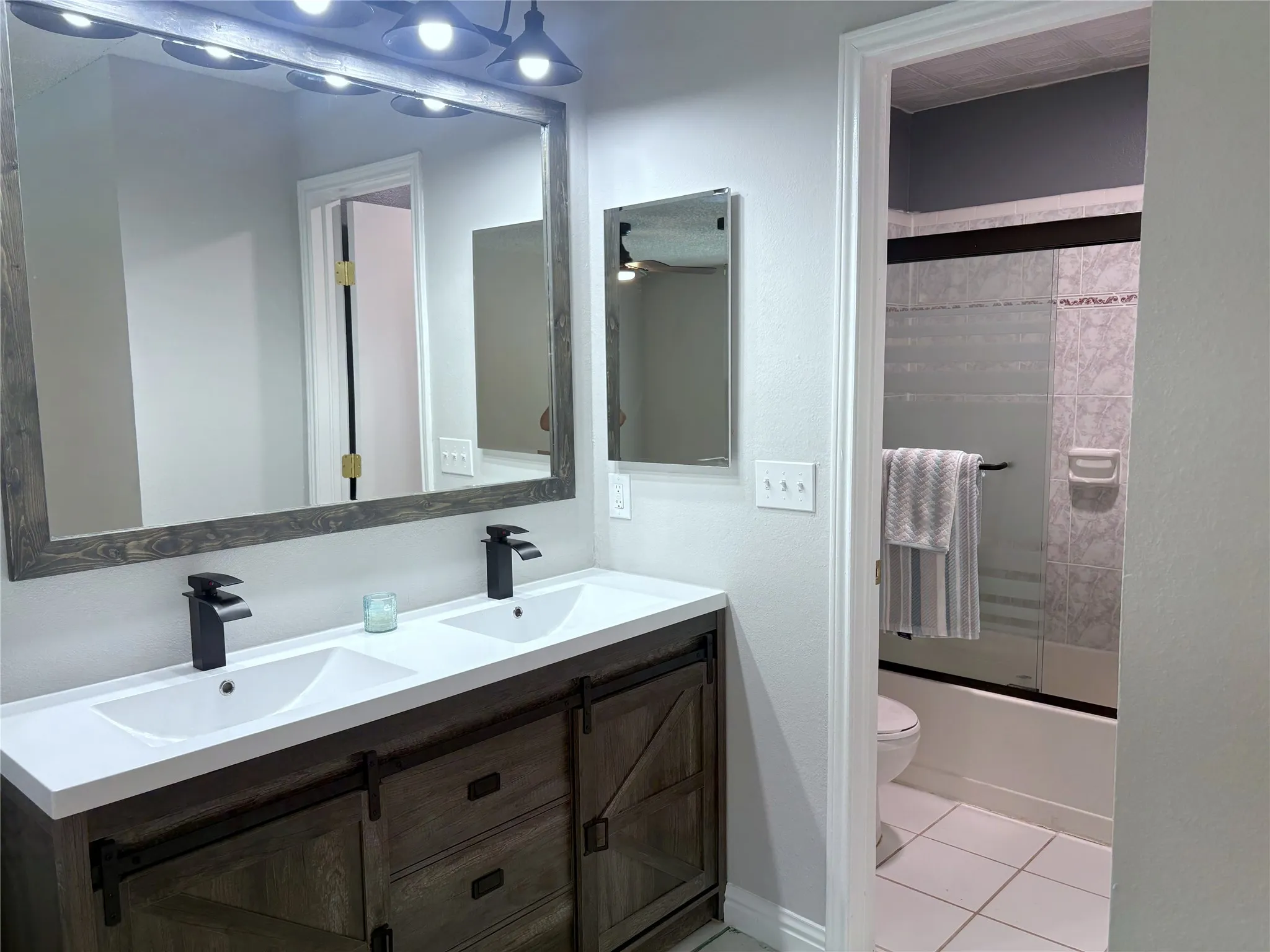 The master vanities match the barn doors, and updated fixtures include a mirrored medicine cabinet.
