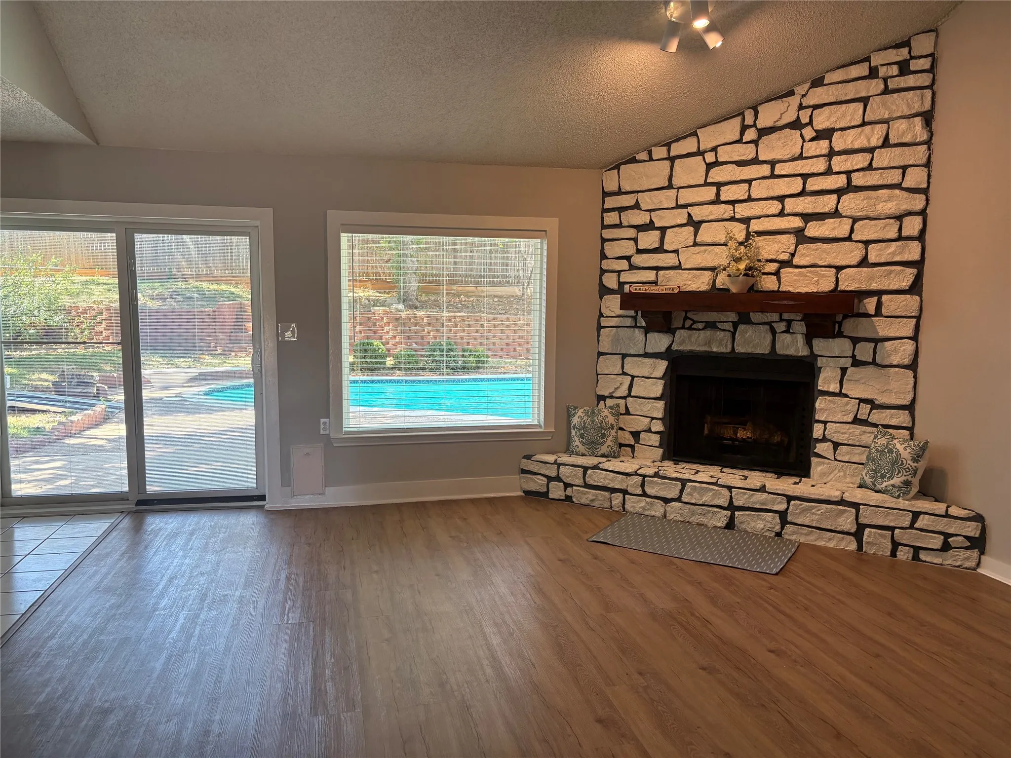 The gracious living room features a stone fireplace, vaulted ceiling, and serene pool views.