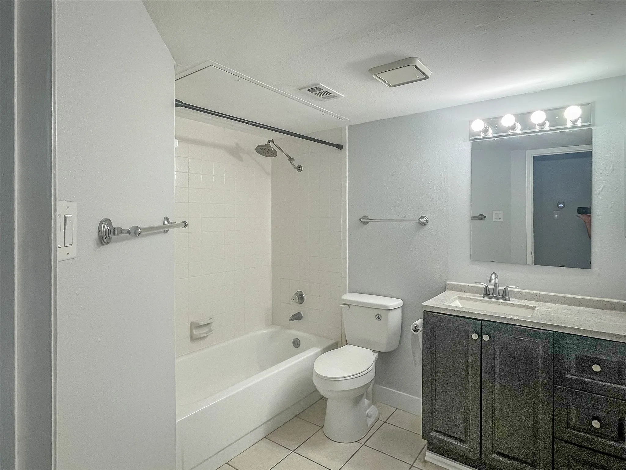 Vanity with dark wood-finish cabinetry, light-colored countertop, and integrated sink