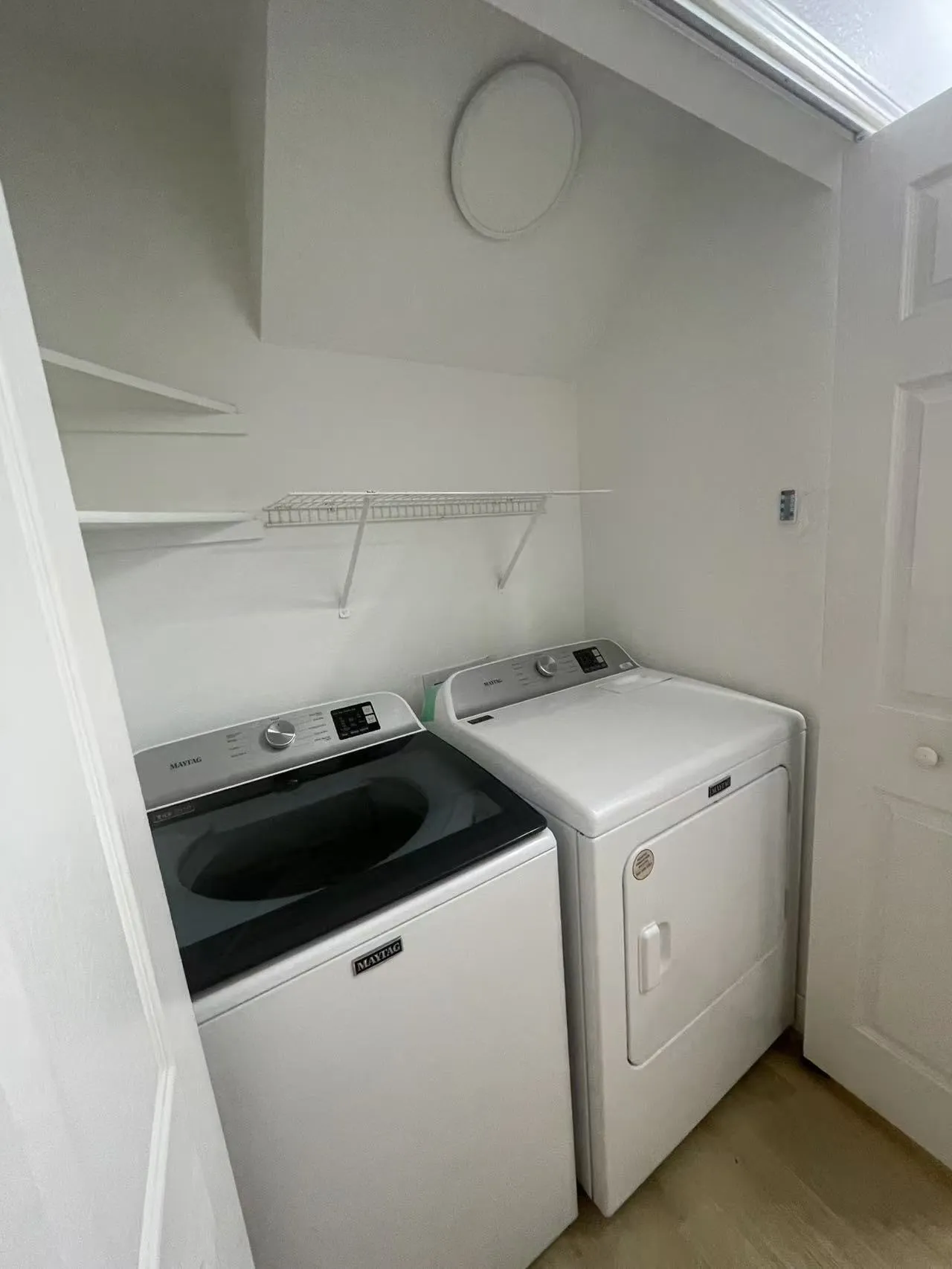 Dedicated laundry area with built-in shelving, wire rack storage, and full-size appliances