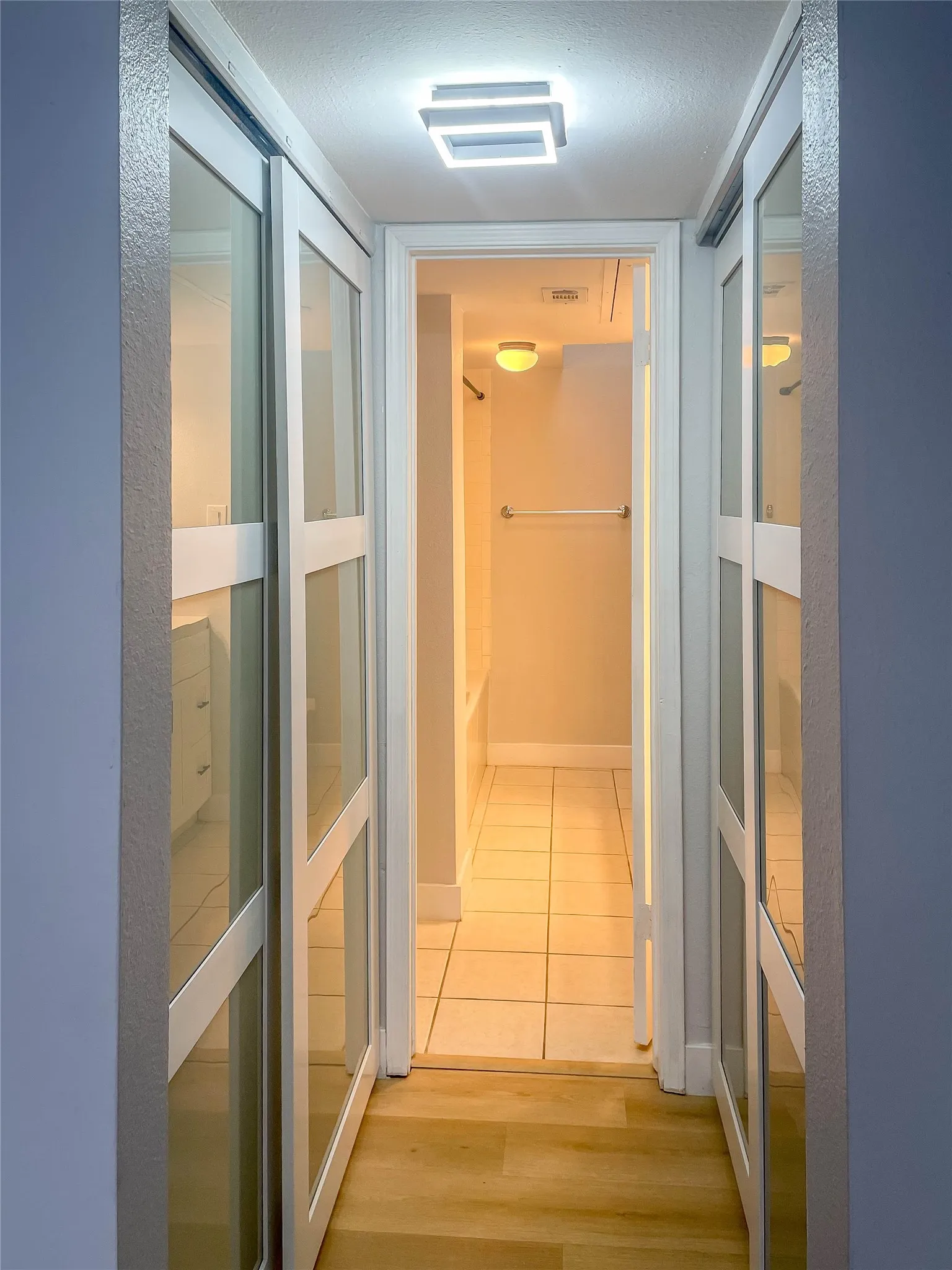 Recessed lighting fixture, wood-finish flooring, sliding closet doors with frosted glass panels, tiled flooring