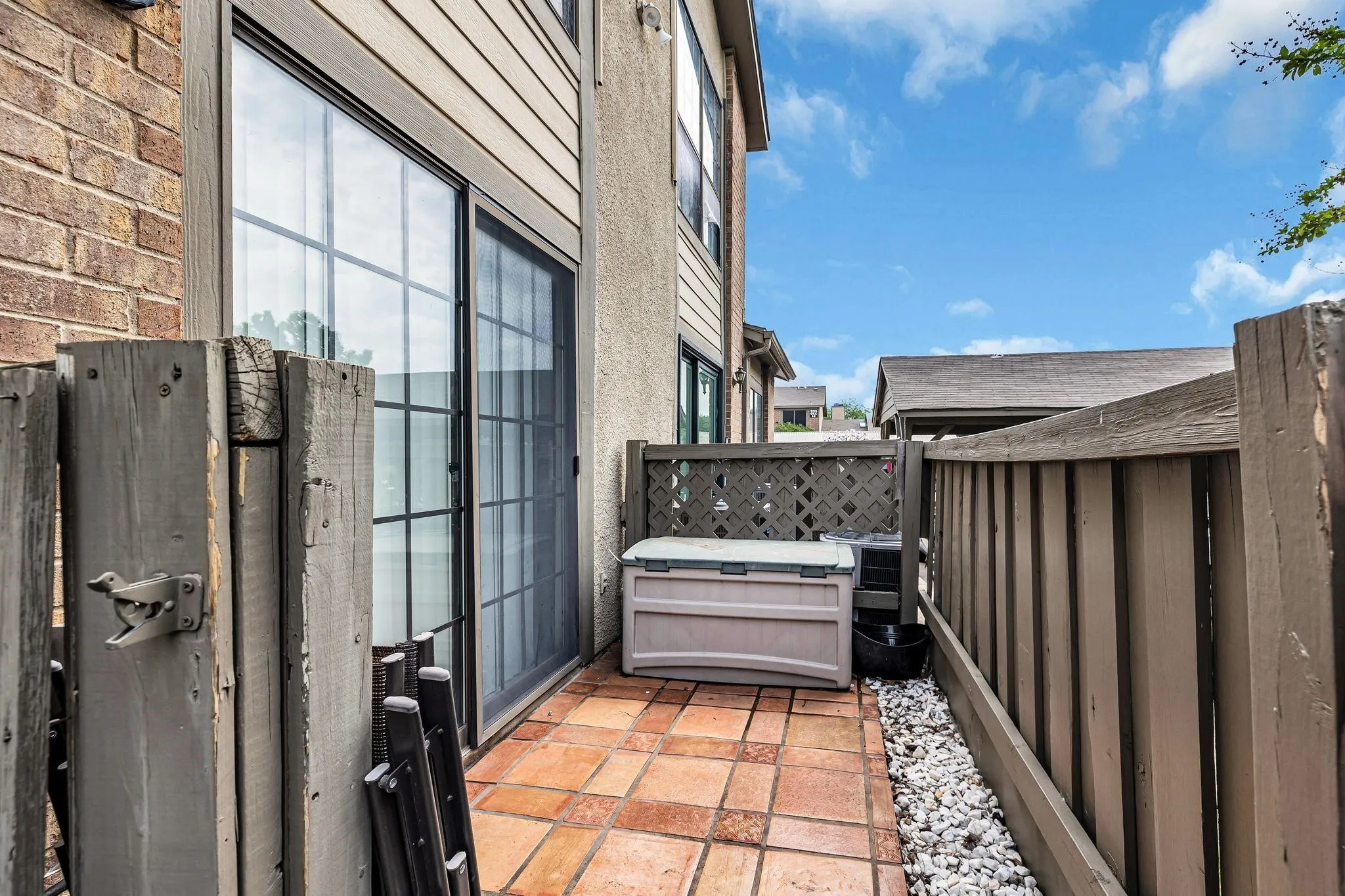 Tiled patio with a sliding glass door and wood fencing