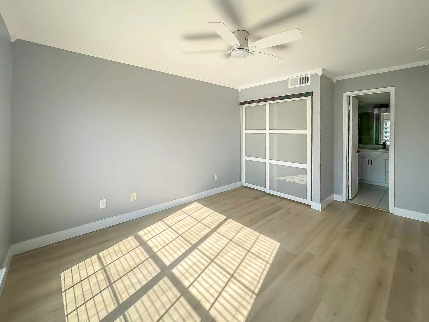 Wood-finish flooring with crown molding and baseboards