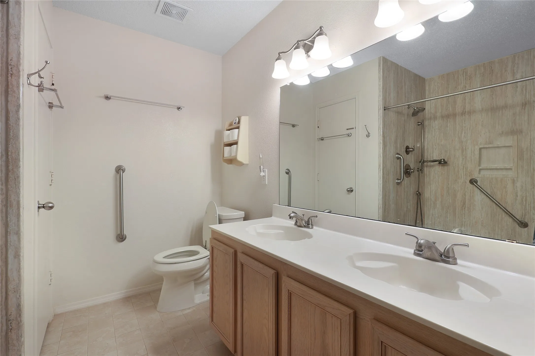 Dual vanity with integrated sinks, brushed nickel fixtures, wood-finish cabinetry, and a full-width mirror
