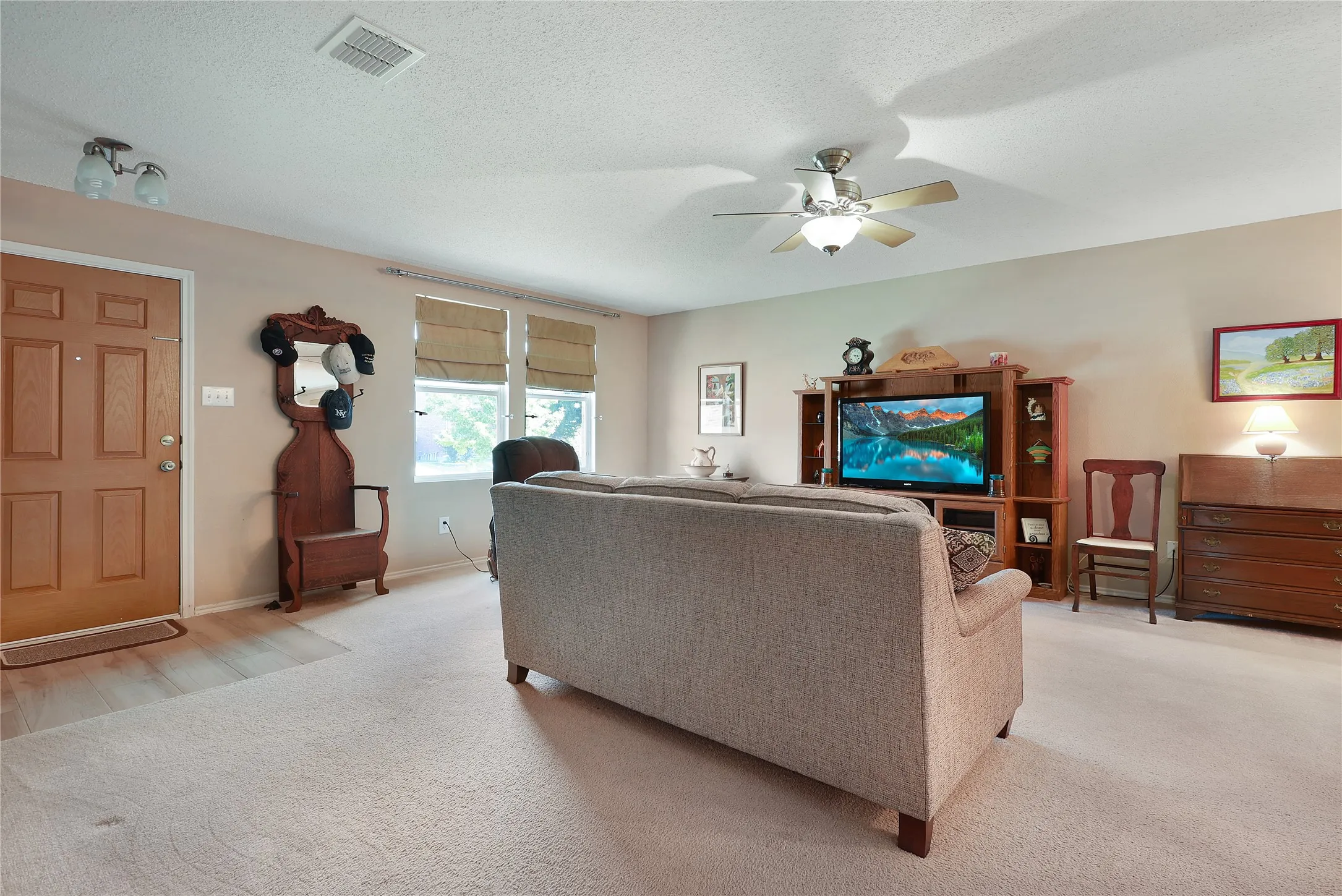 Recessed lighting, ceiling fan with integrated lighting, wood-finish flooring, paneled entry door, multiple windows with blinds