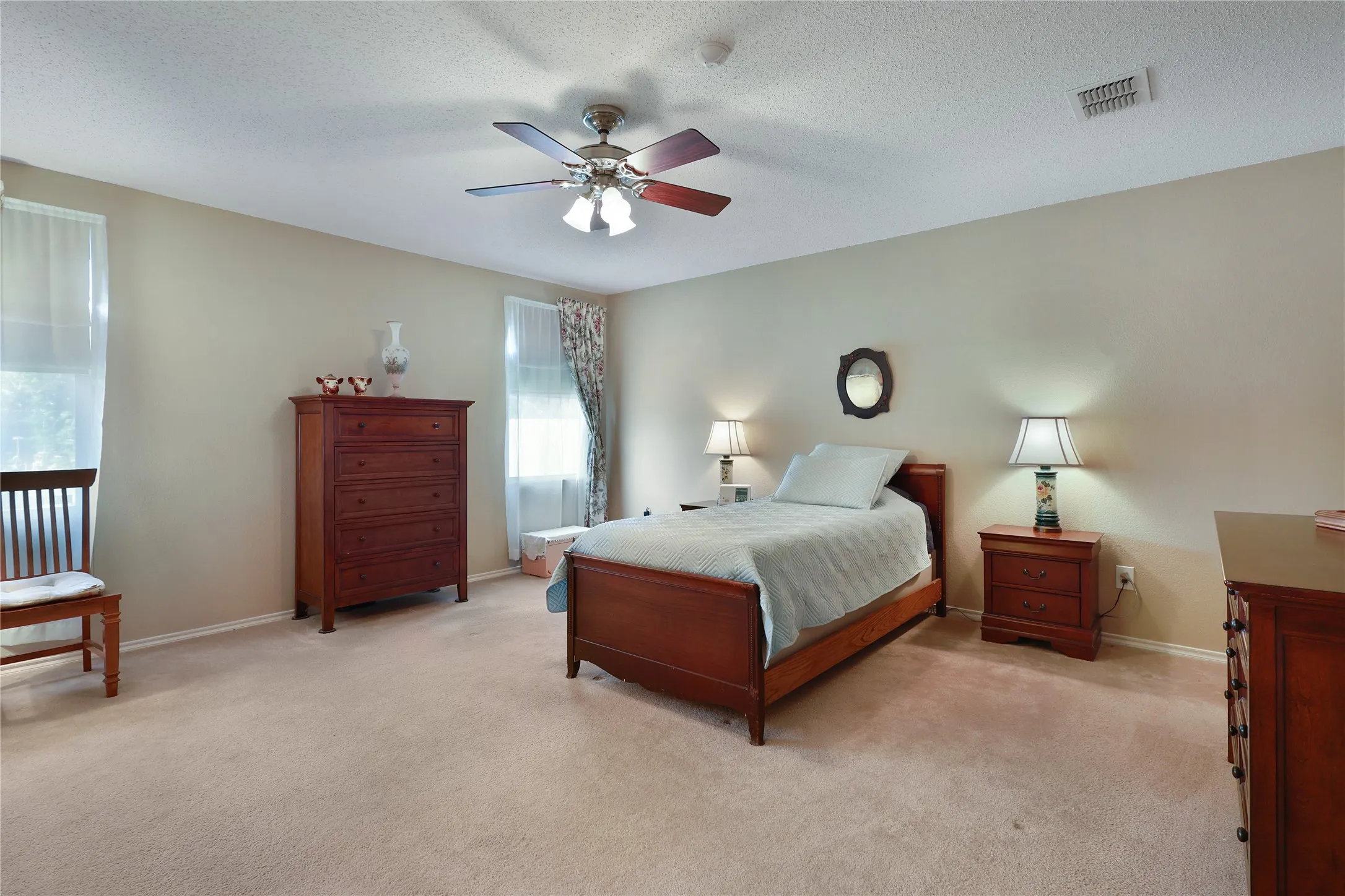 Neutral wall paint, plush carpeting, ceiling fan with light fixture, and windows with natural light