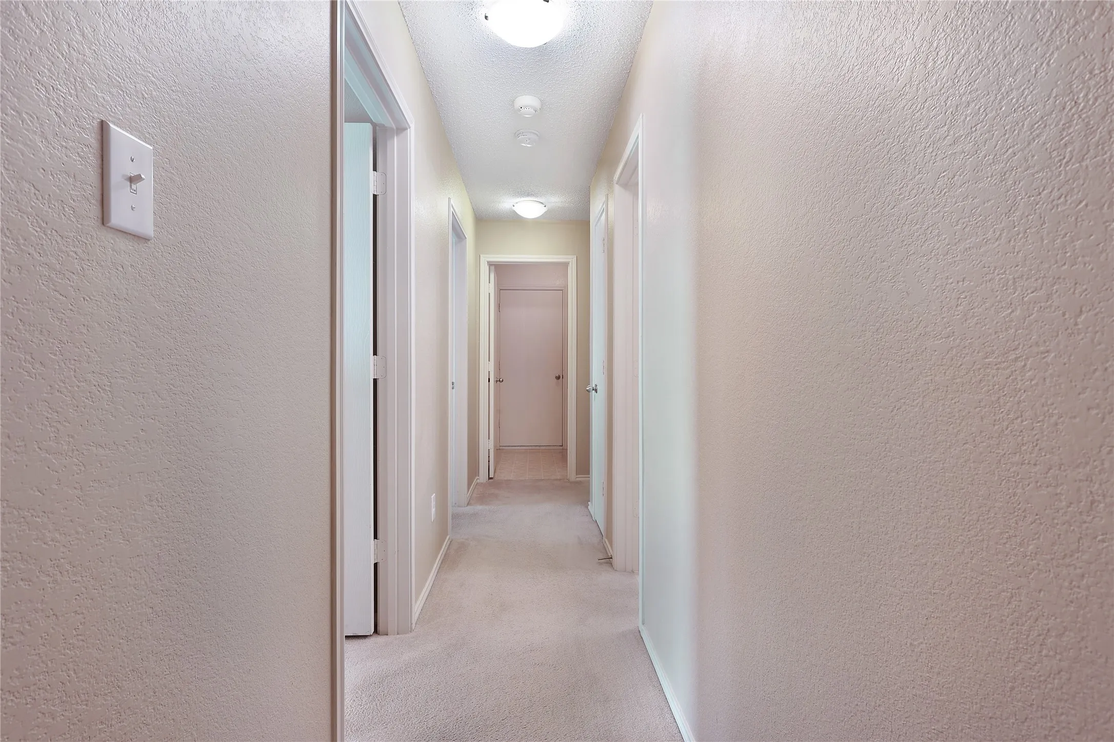 Hallway featuring light-toned carpeting and flush-mount ceiling lighting