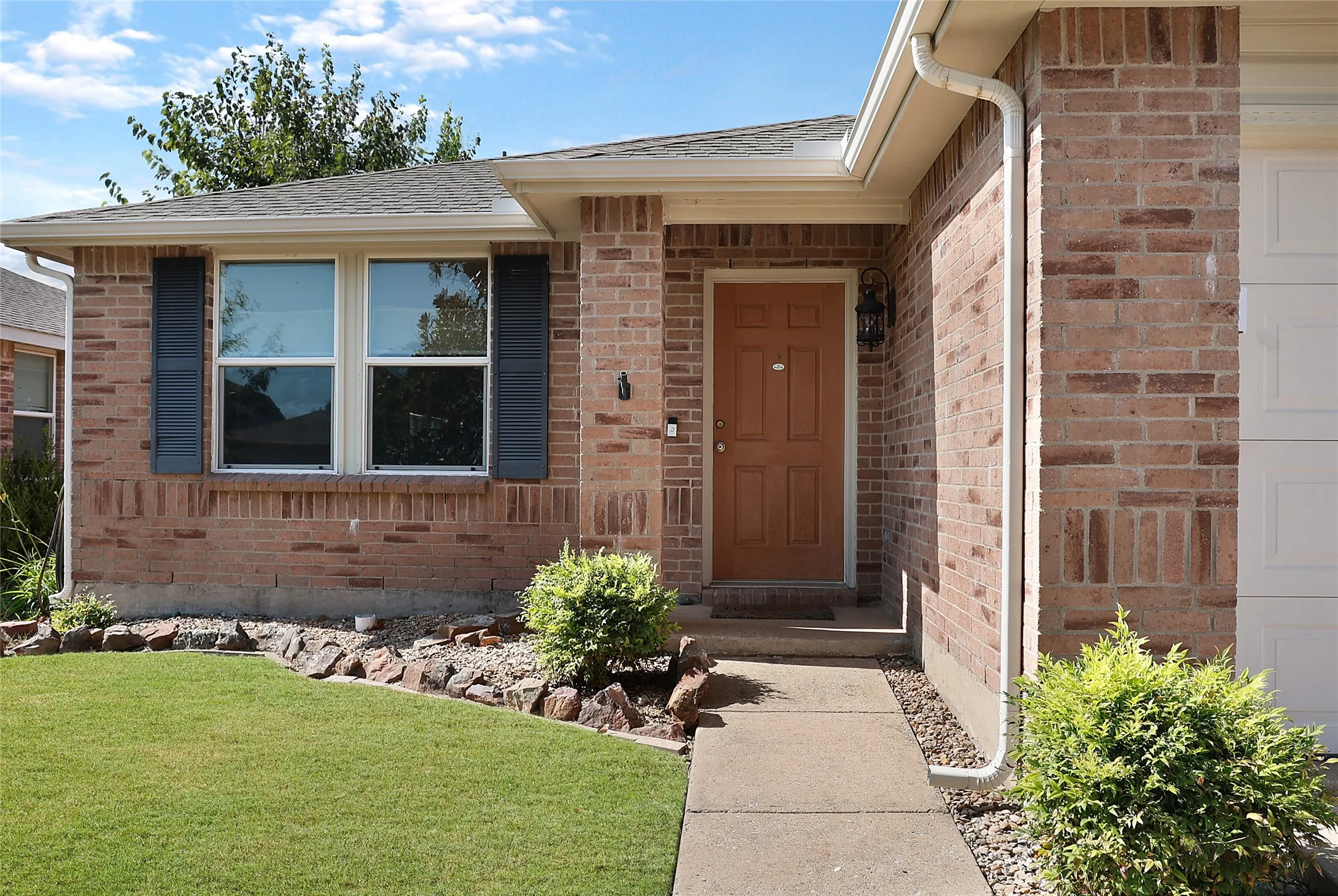 Brick exterior with white window frames and dark shutters