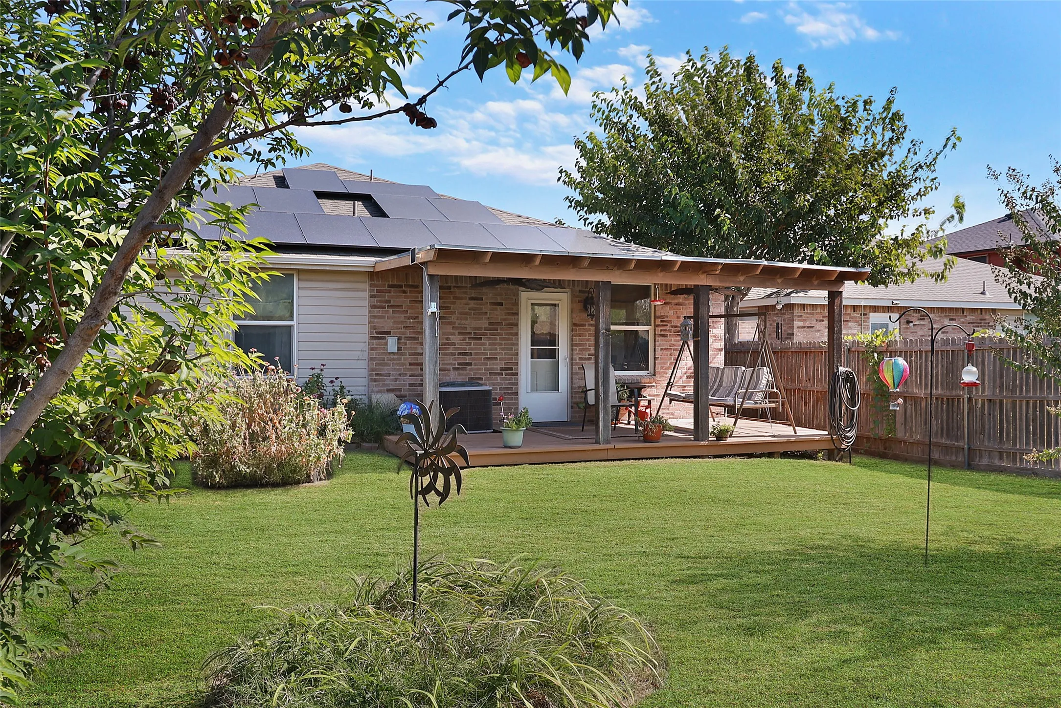 Expansive backyard featuring a covered patio, wood-finish decking, and solar panels