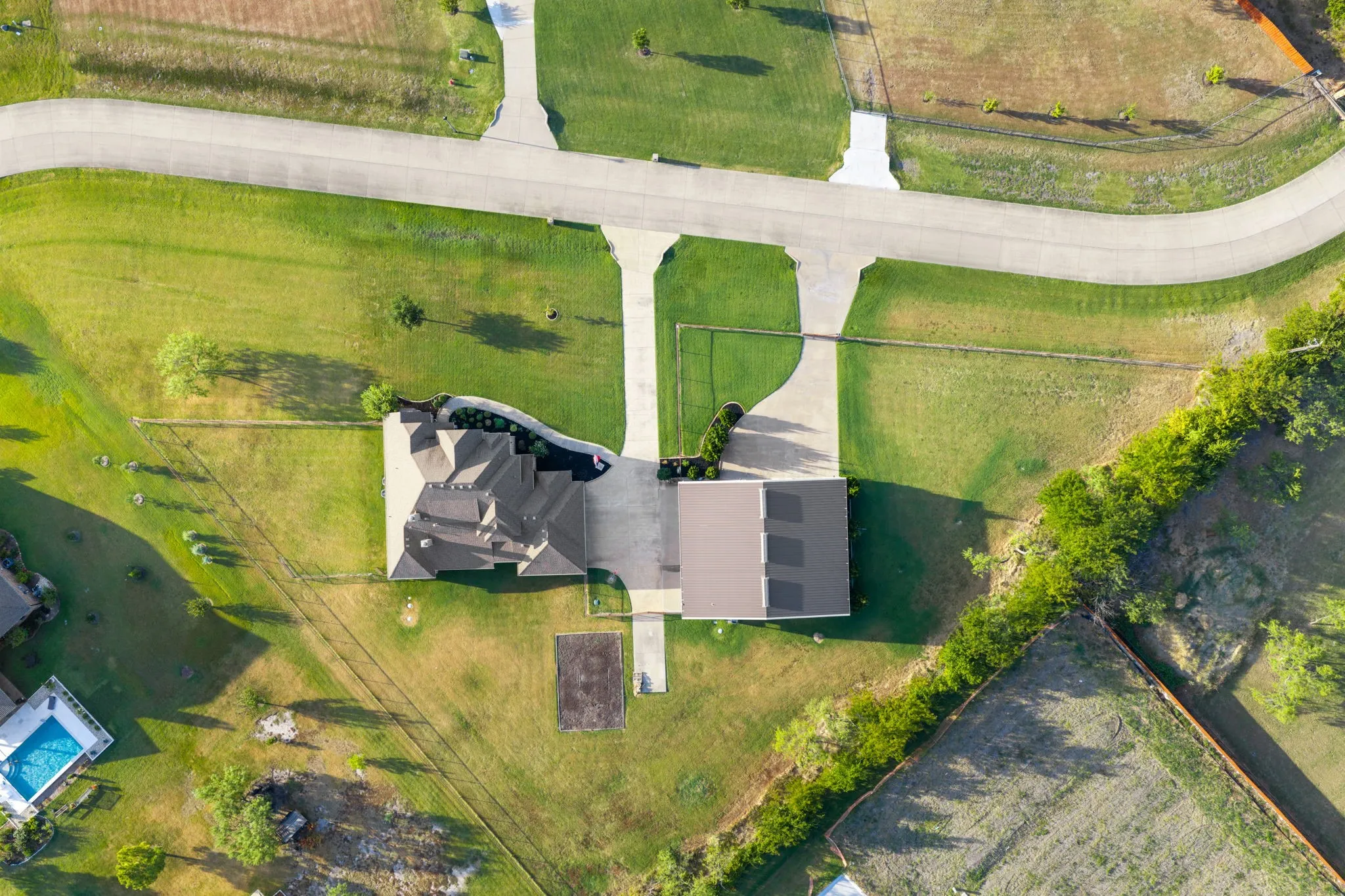 Expansive property with a large residence, separate detached structure, and extensive paved driveway
