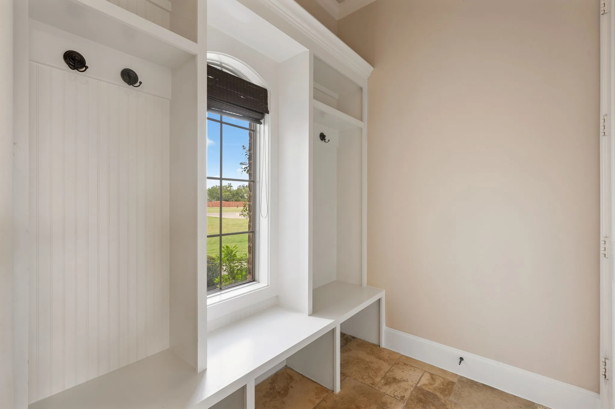 Built-in storage area featuring white cabinetry, integrated seating, and a grid-patterned window