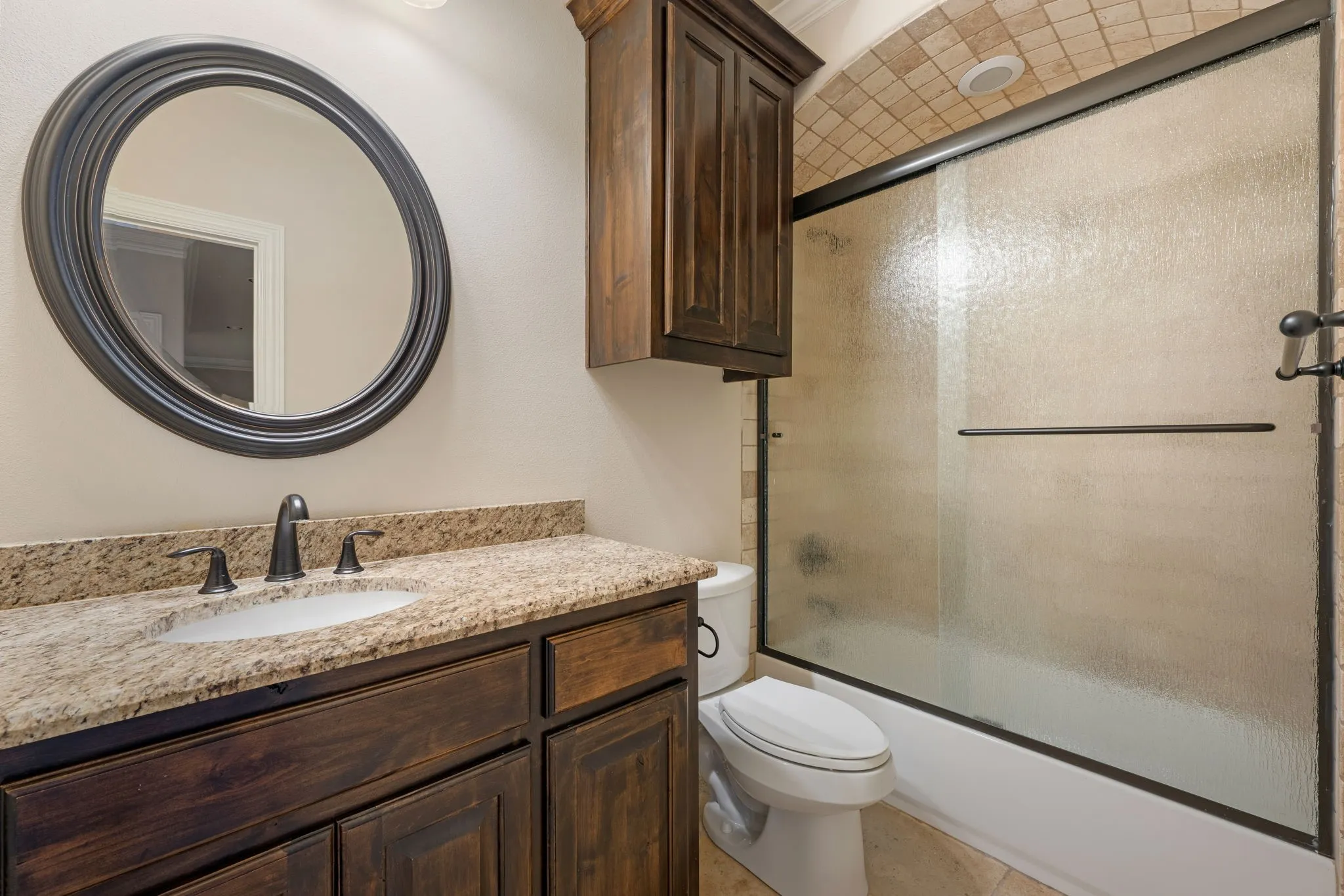Vanity with a granite countertop, undermount sink, and dark wood-finish cabinetry