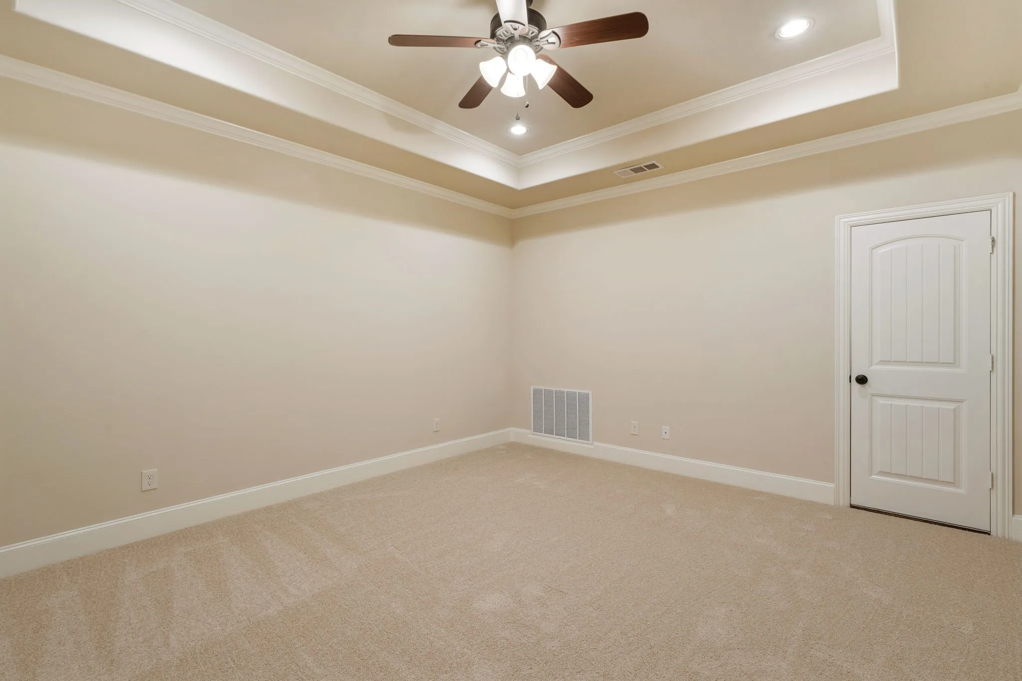 Tray ceiling with crown molding, recessed lighting, ceiling fan, and light-colored carpeting