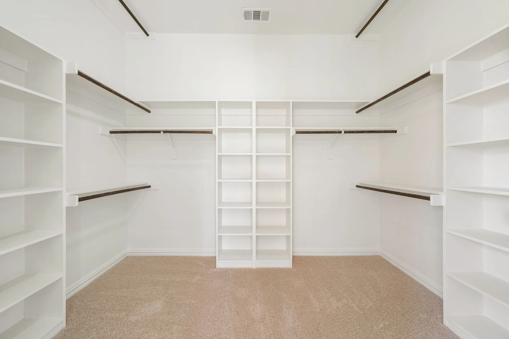 Walk-in closet with built-in shelving, hanging rods, and carpet flooring